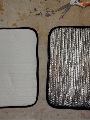 2 completed fabric covered RV window shades, one showing the fabric side, the other showing the reflectix side.