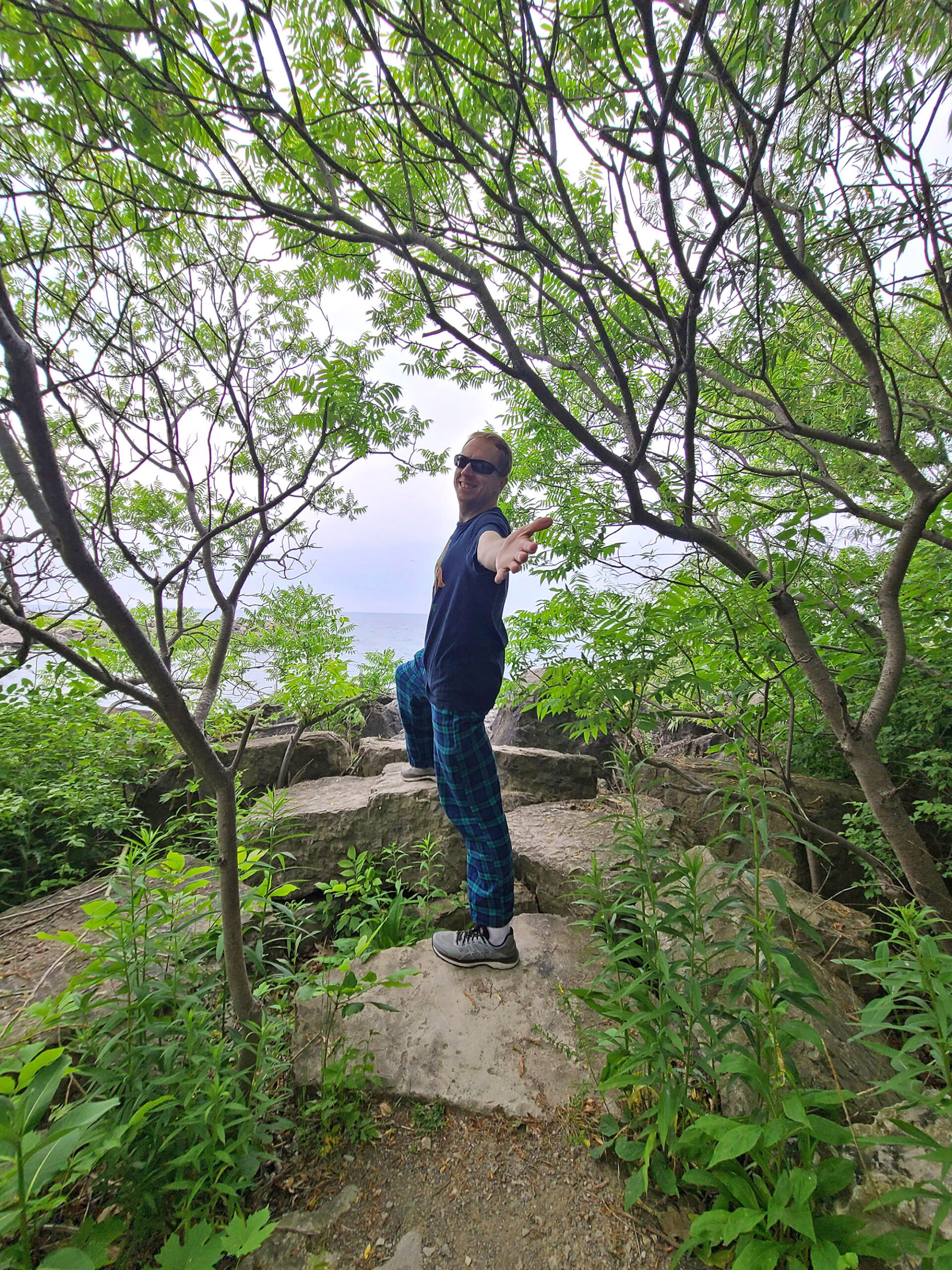 A middle aged man in the woods extending a hand back to the photographer.
