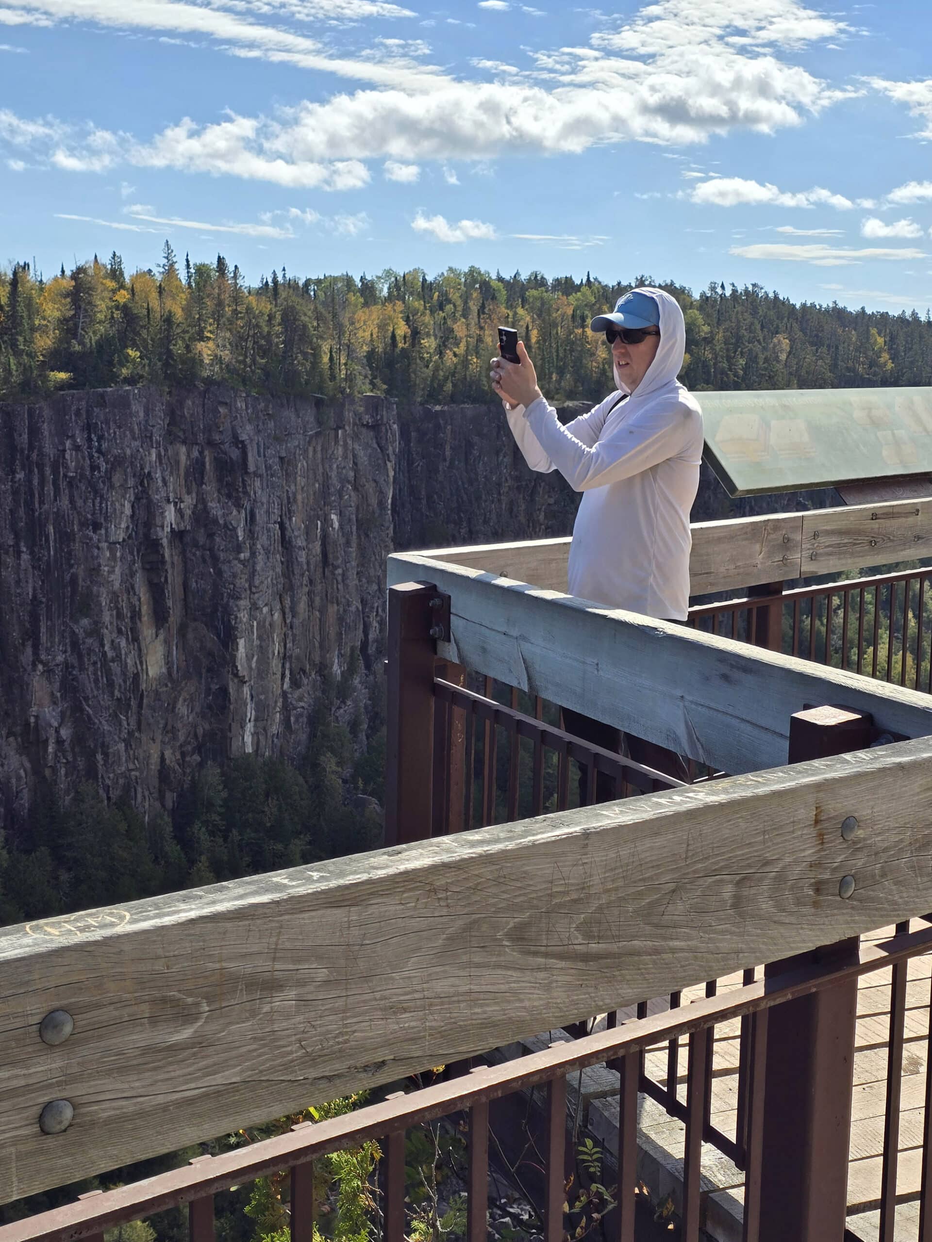 A man standing on a viewing platform to photograph ouimet canyon.