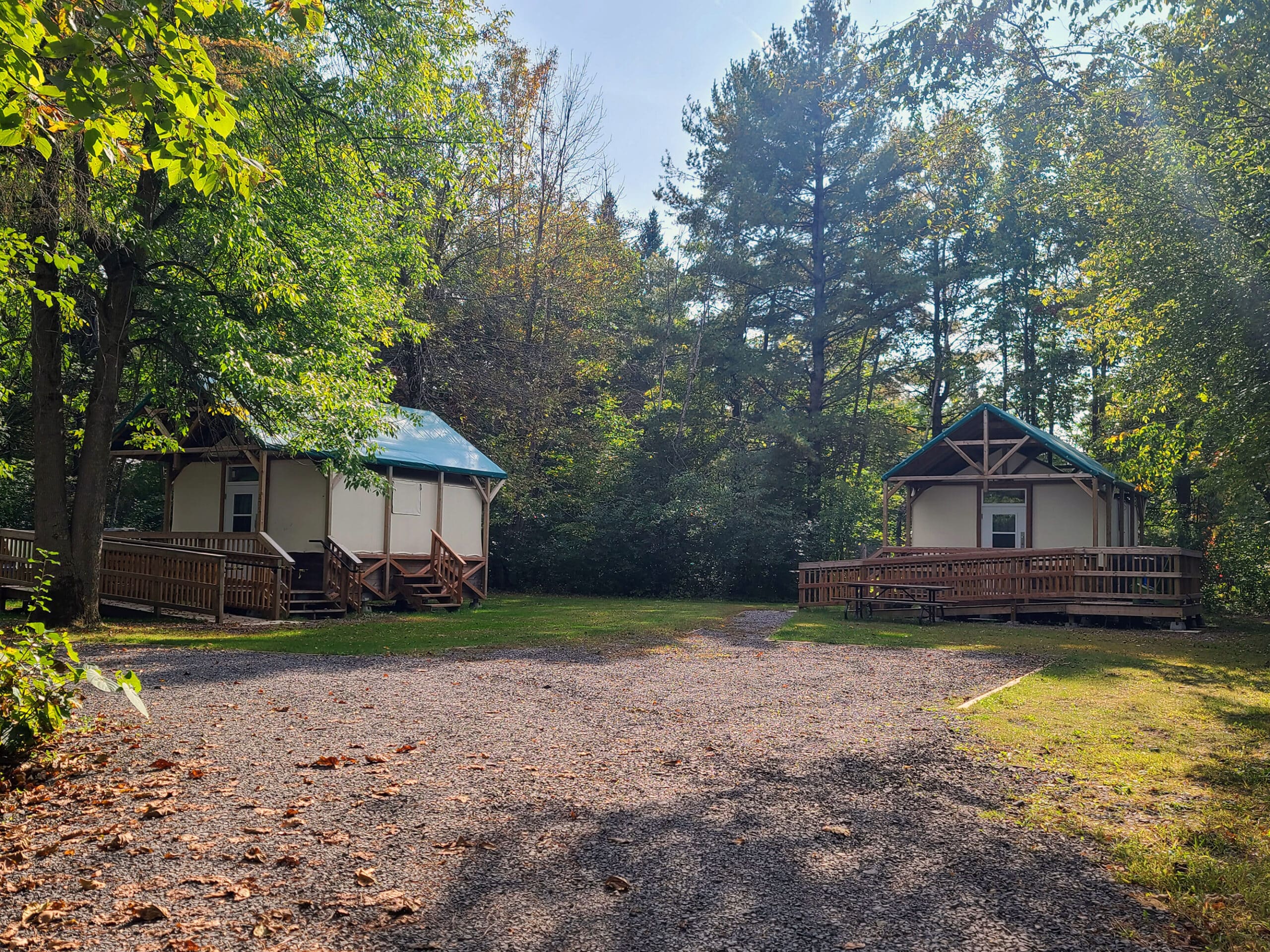 2 soft sided cabins with woods in the background.