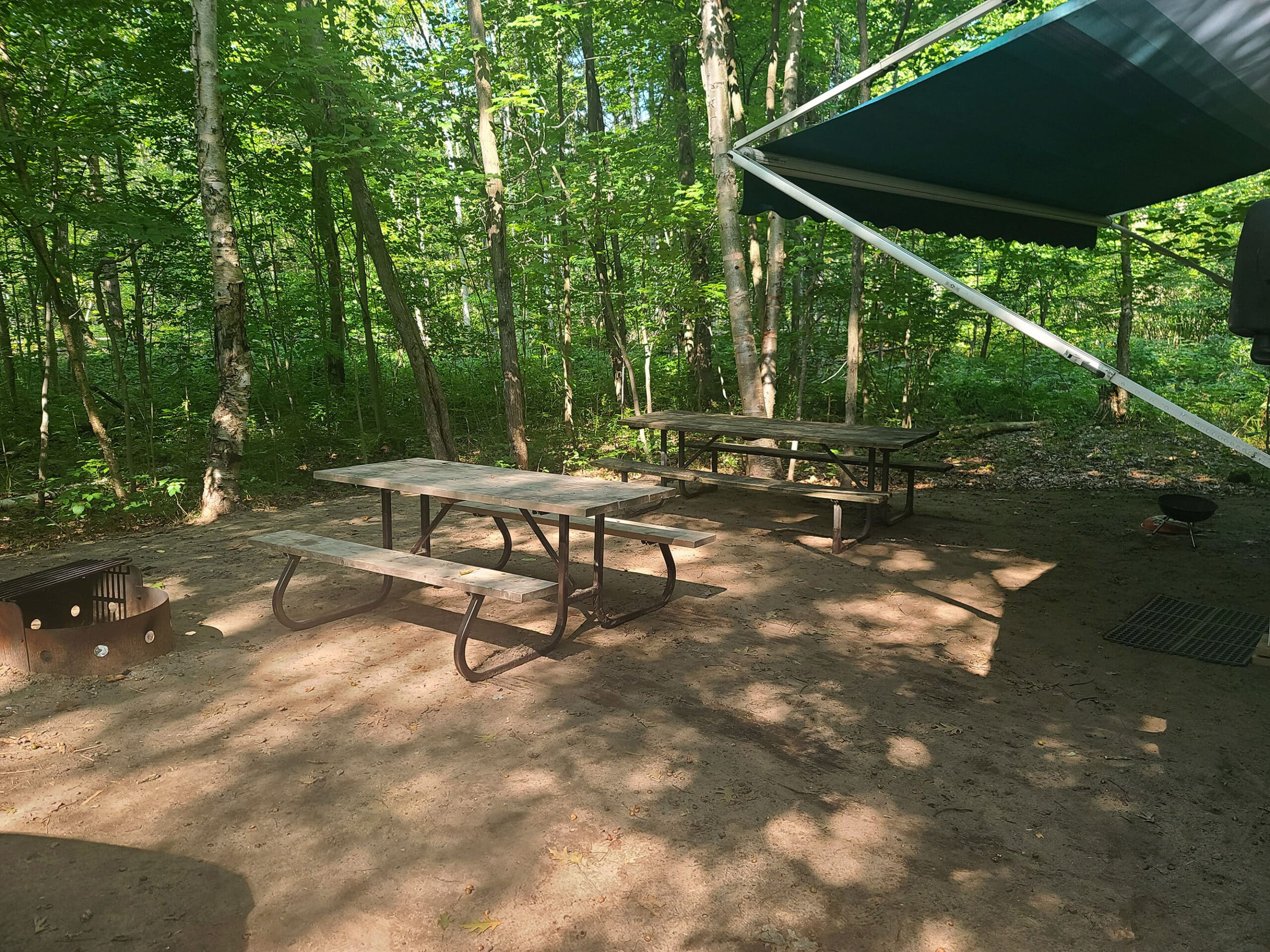 A campsite with 2 picnic tables.