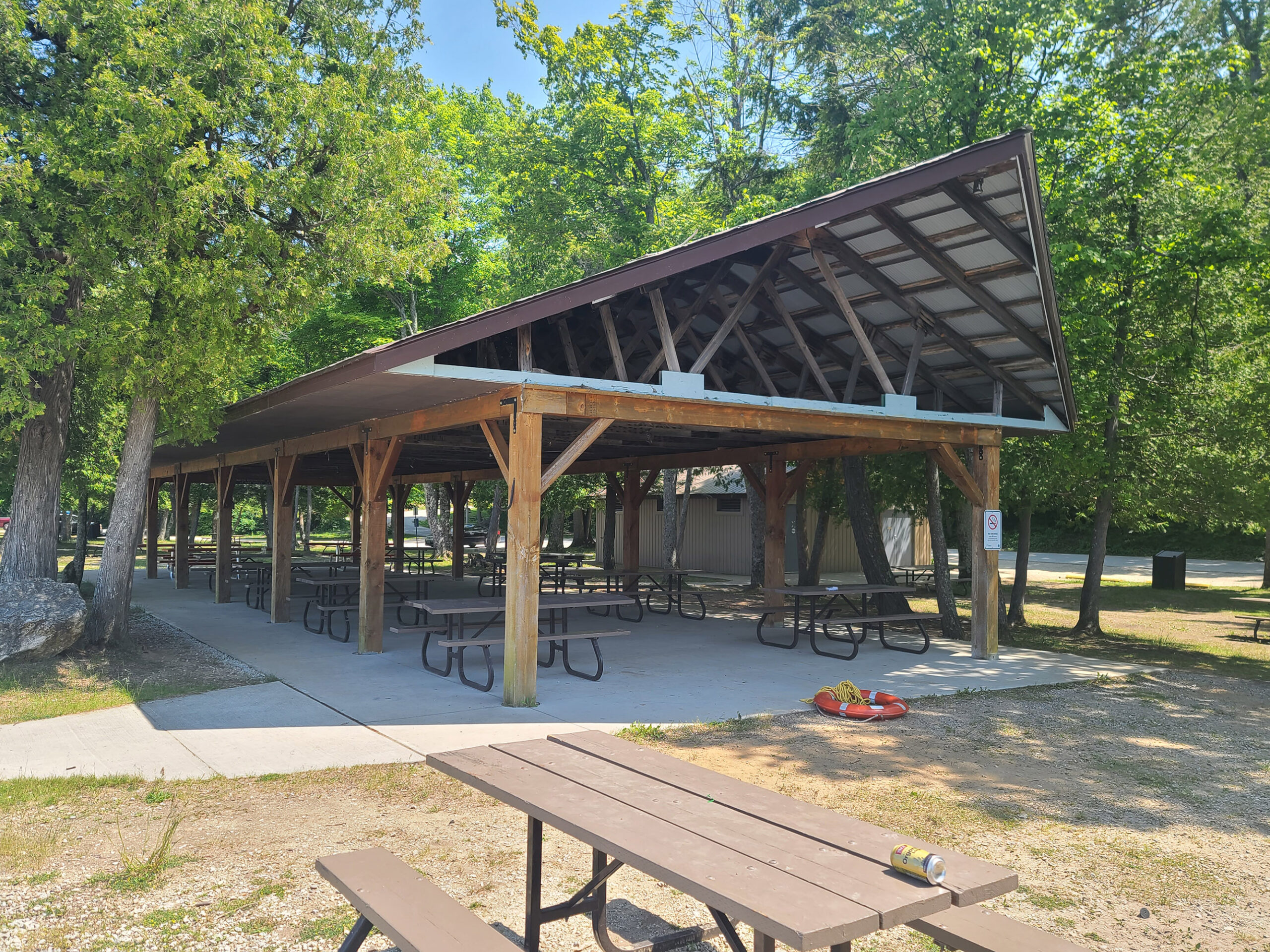 A large, open wooden pavilion structure, with picnic seating underneath.