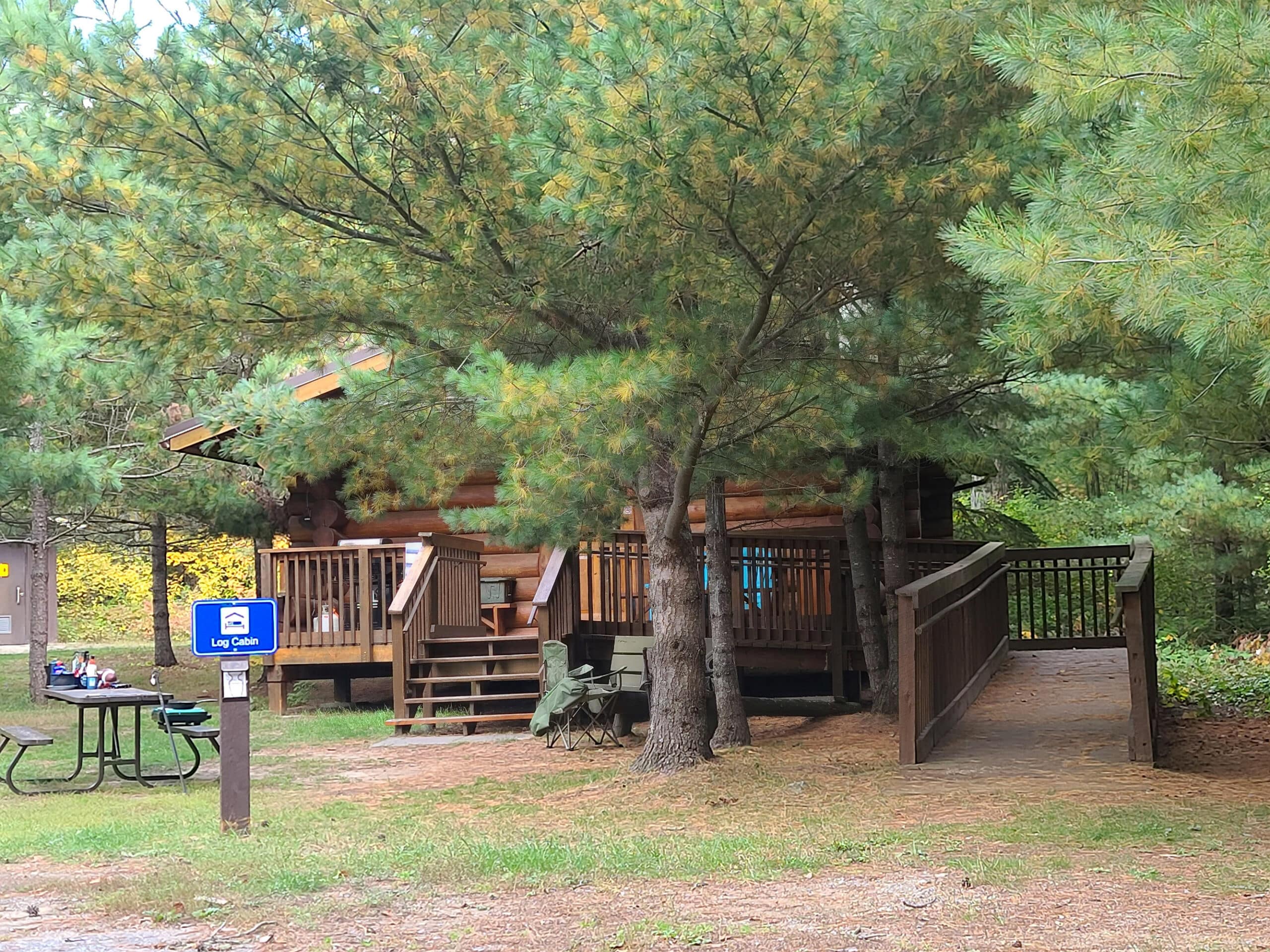 A wooden cabin, partially obscured by trees in front of it.