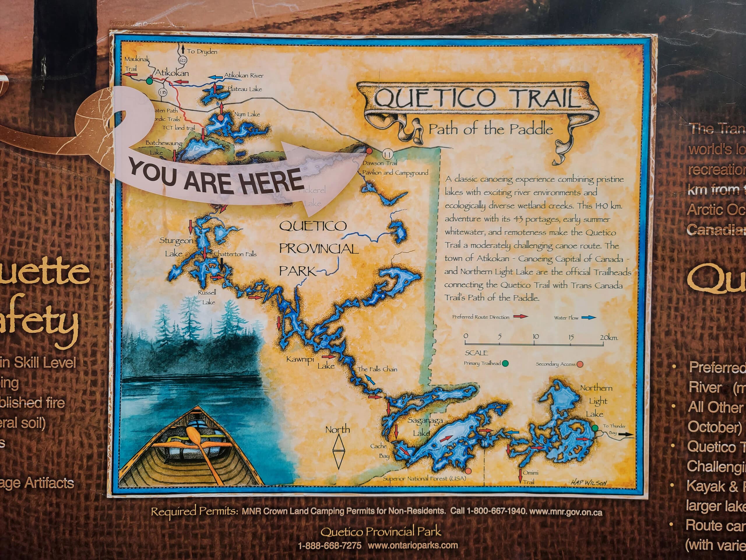 An old timey looking sign for Quetico trail, with a large you are here and lakes indicated.