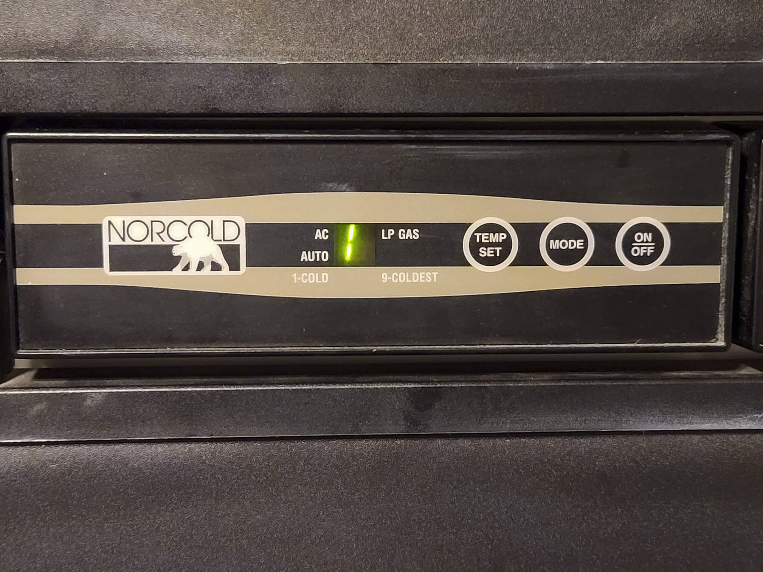 The control panel of an RV fridge. Green lights indicate auto mode, and AC power selected.