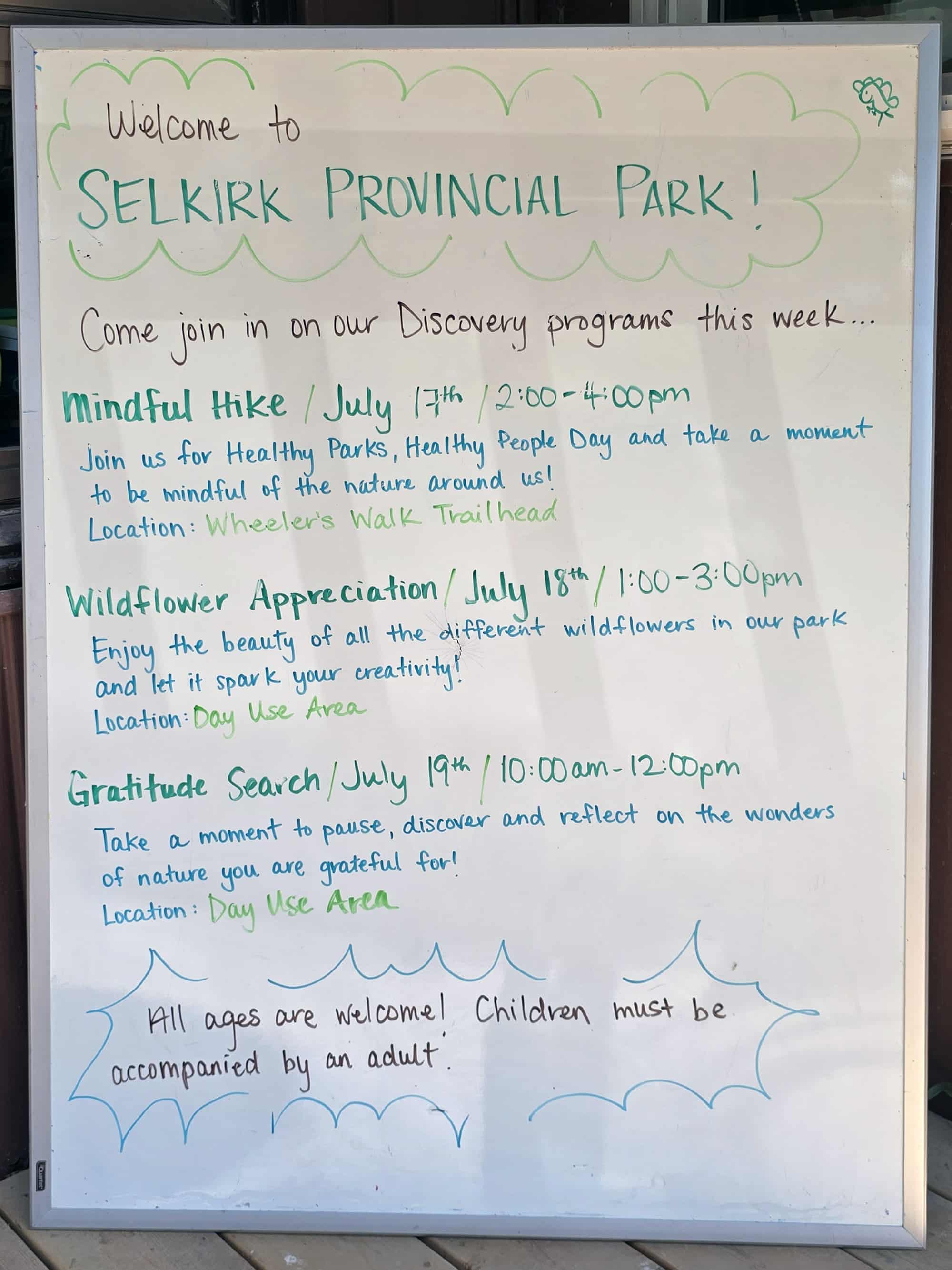 A whiteboard with the Selkirk Provincial Park discovery programming schedule written on it.