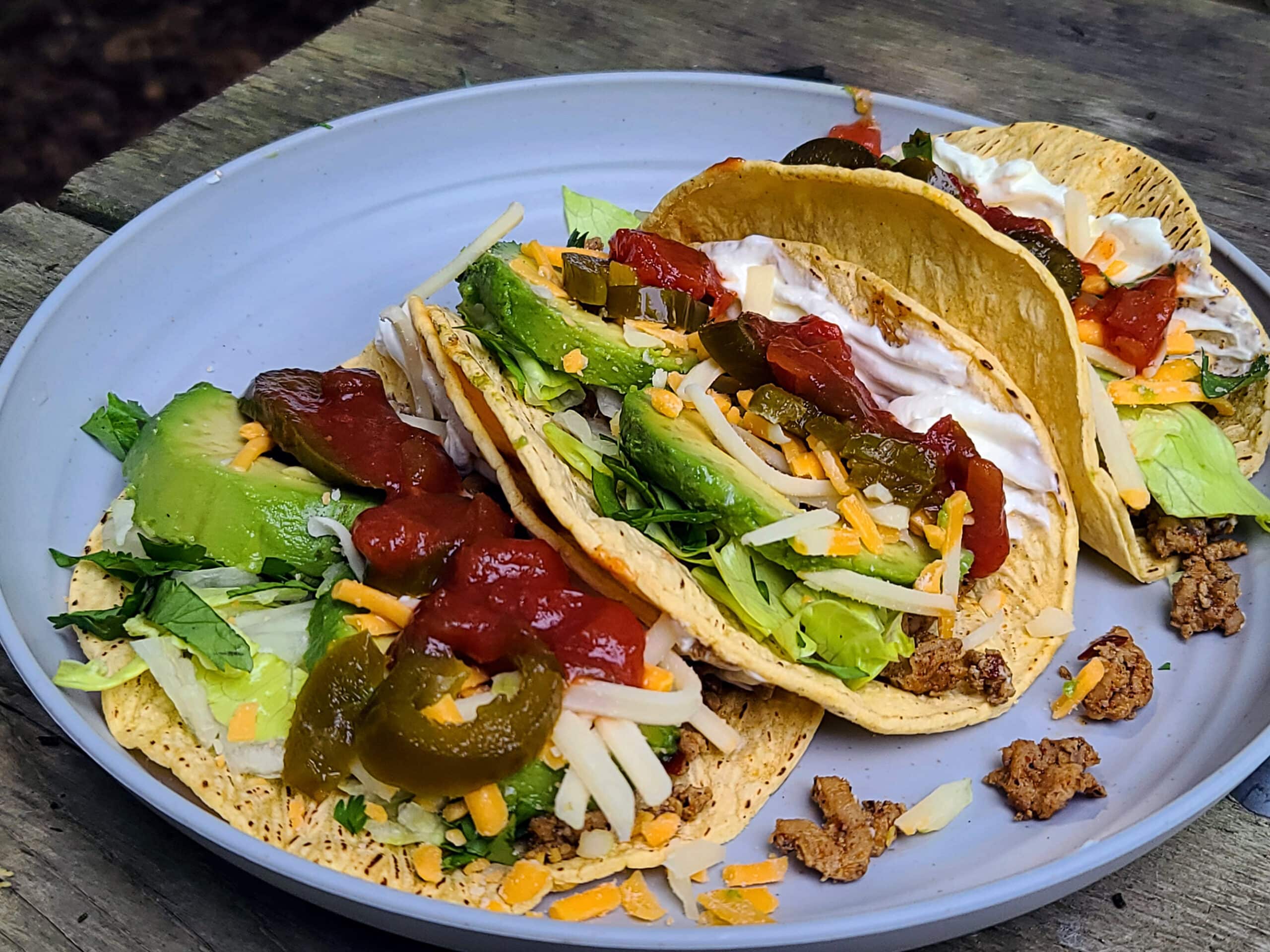 A paper plate with 3 traditional style camping tacos on it.