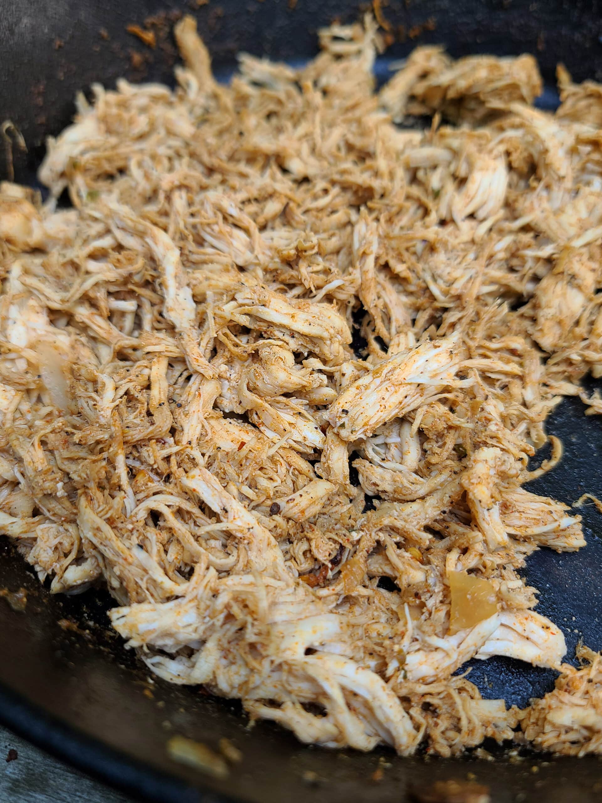 Taco`  seasoned dutch oven pulled chicken, in a cast iron pan.