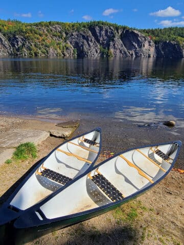 2 canoes on the shore of upper mazinaw lake on a sunny afternoon.