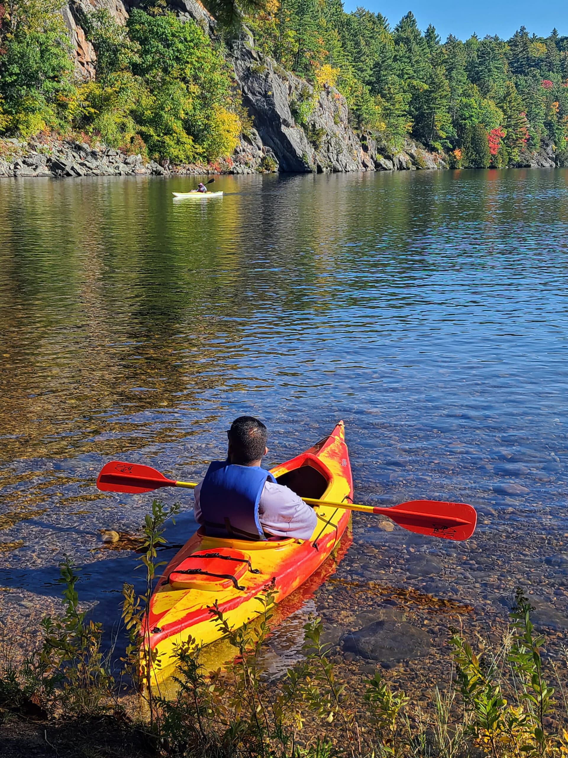 A man in a kayak, about to paddle onto lower mazinaw lake.
