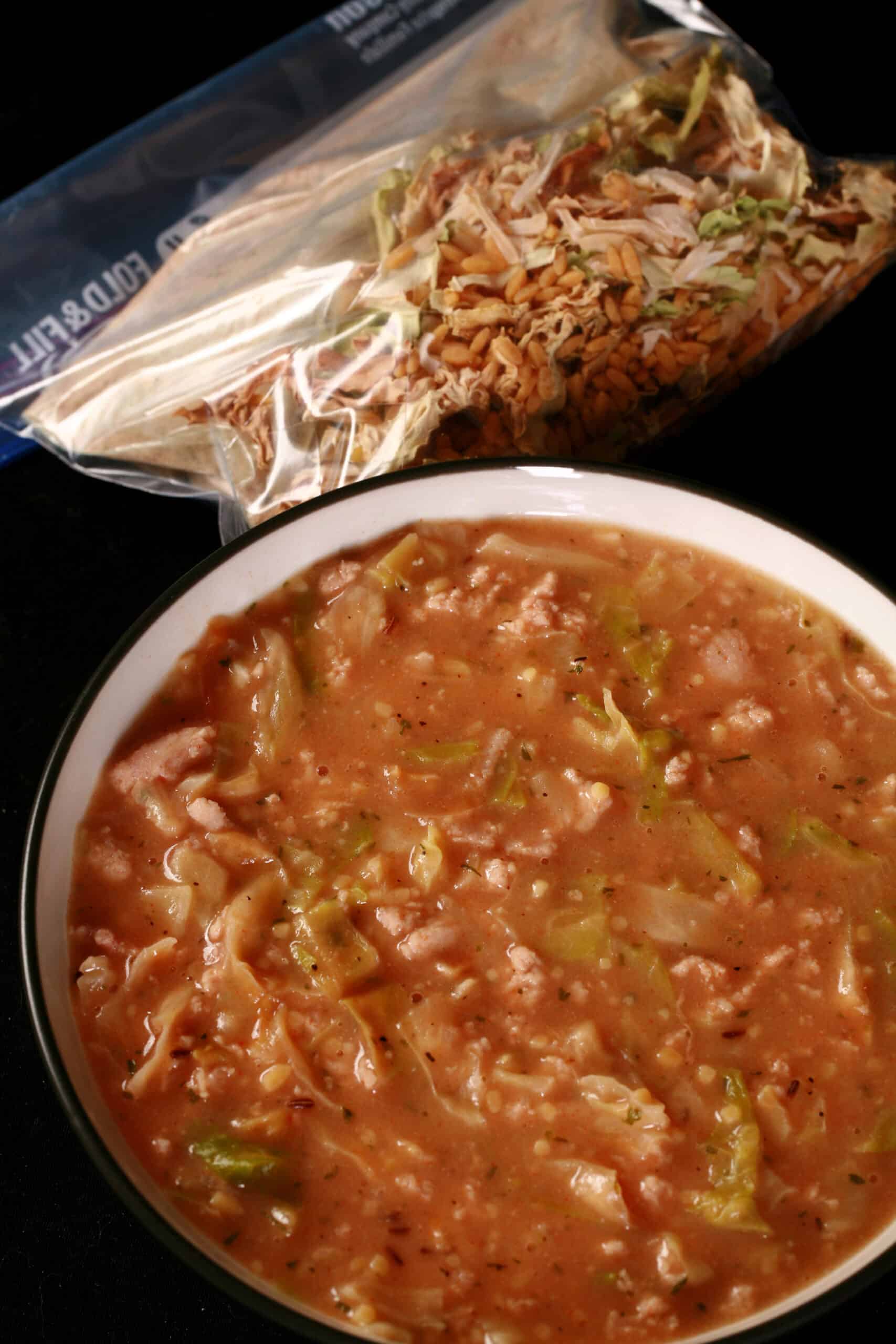 A bowl of cabbage roll soup, in front of a packet of homemade instant soup mix.