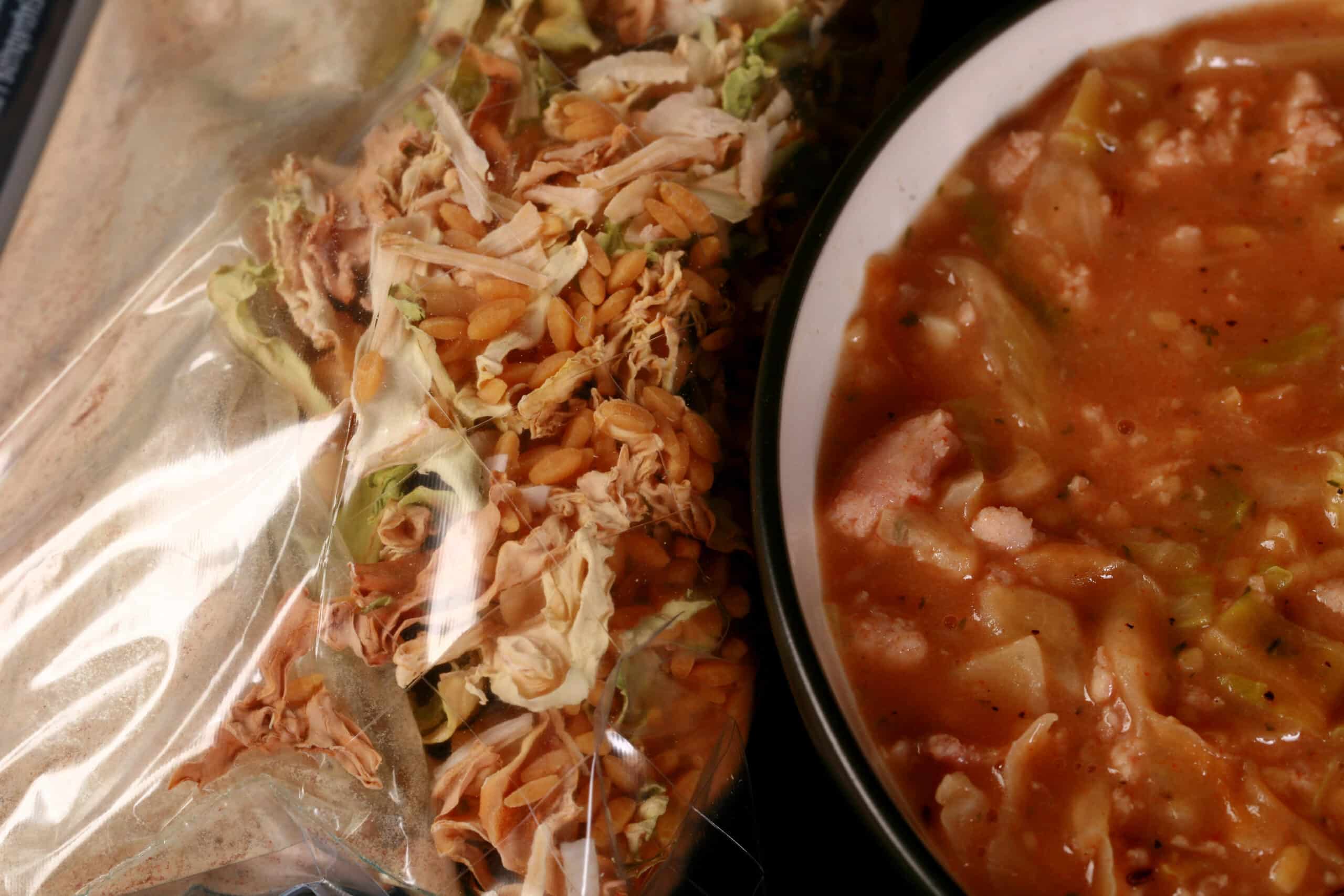 A bowl of cabbage roll soup, next to a packet of homemade instant soup mix.