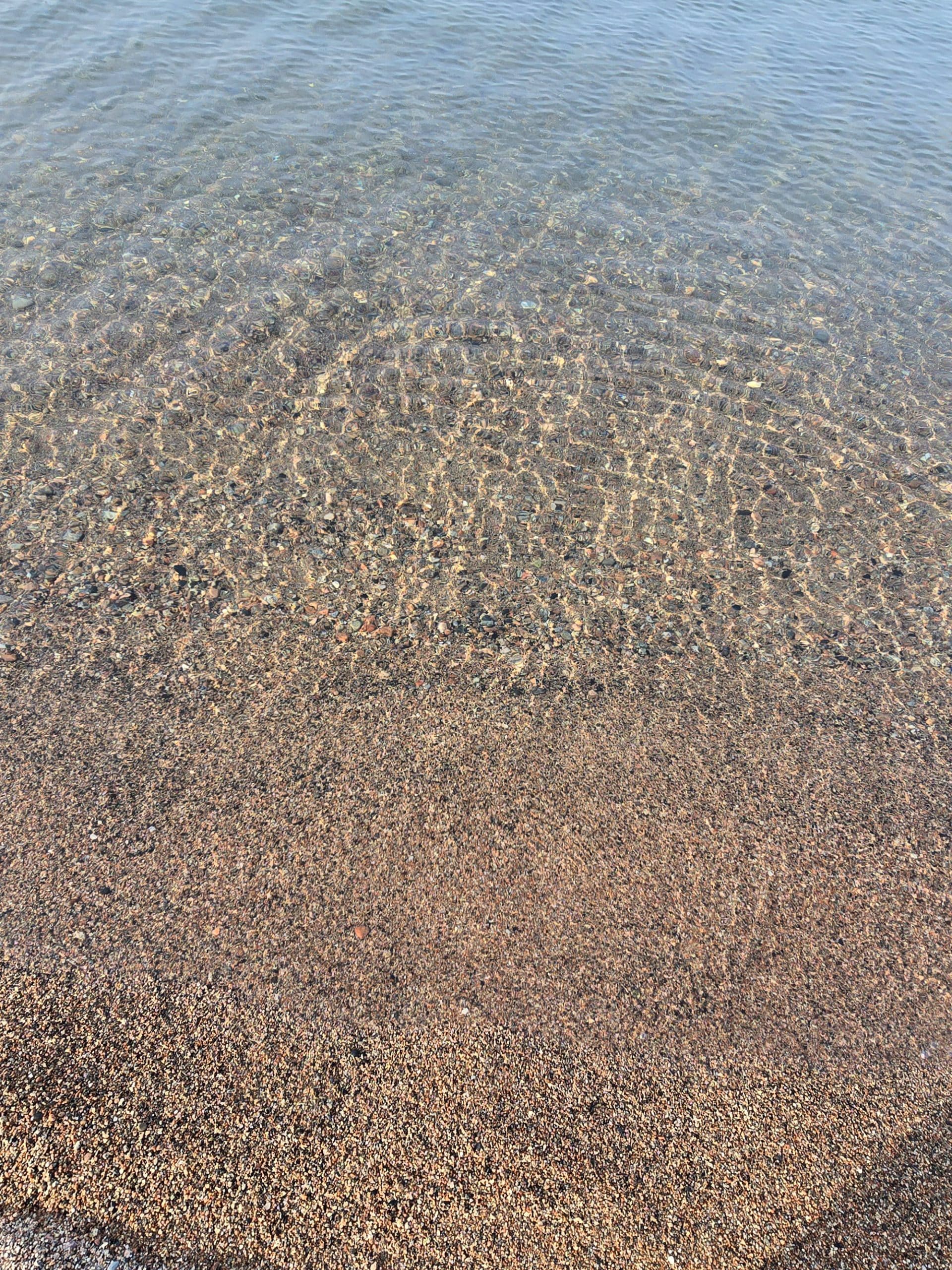 Clear Lake superior water washing over a gravel beach.