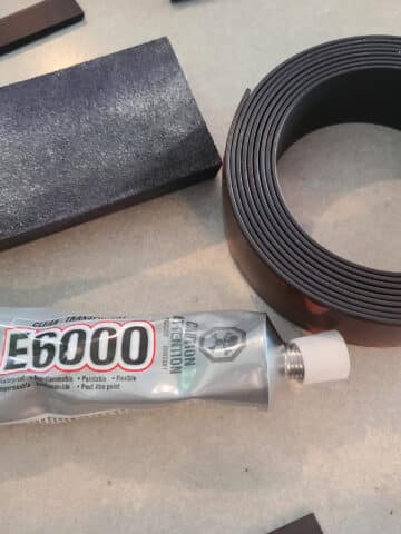 A sandpaper block, a roll of magnet strip, and a tube of E-6000 glue.