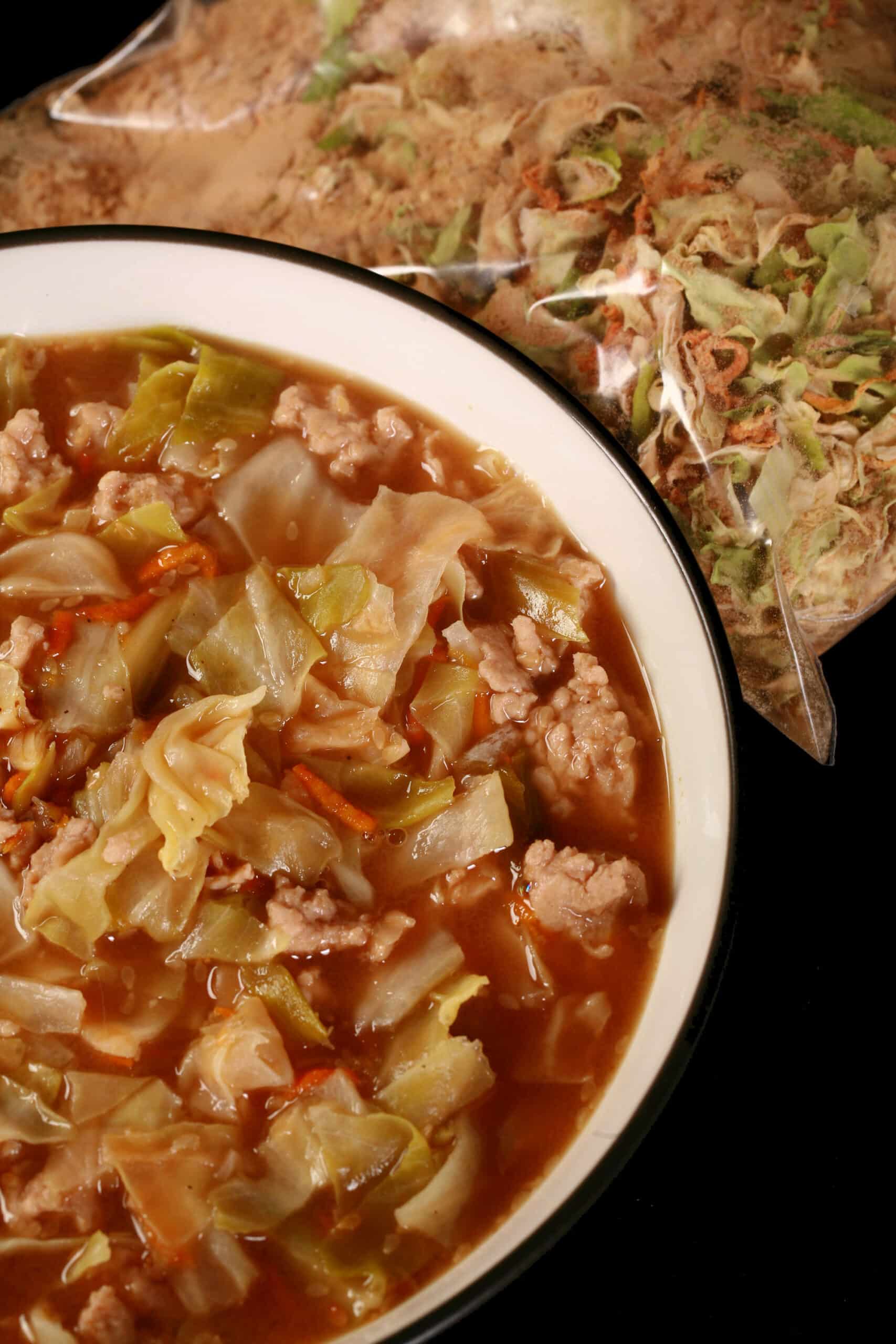 A bowl of gluten free egg roll soup in front of a bag of dry mix for the soup.