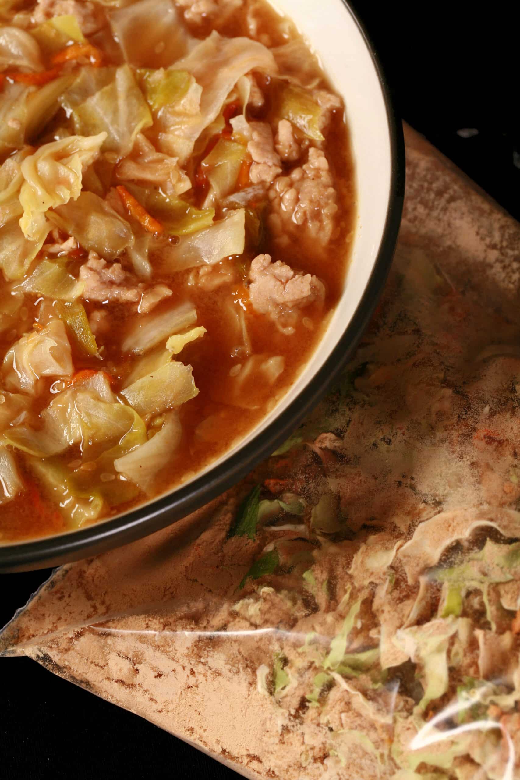 A bowl of gluten free egg roll soup in front of a bag of dry mix for the soup.