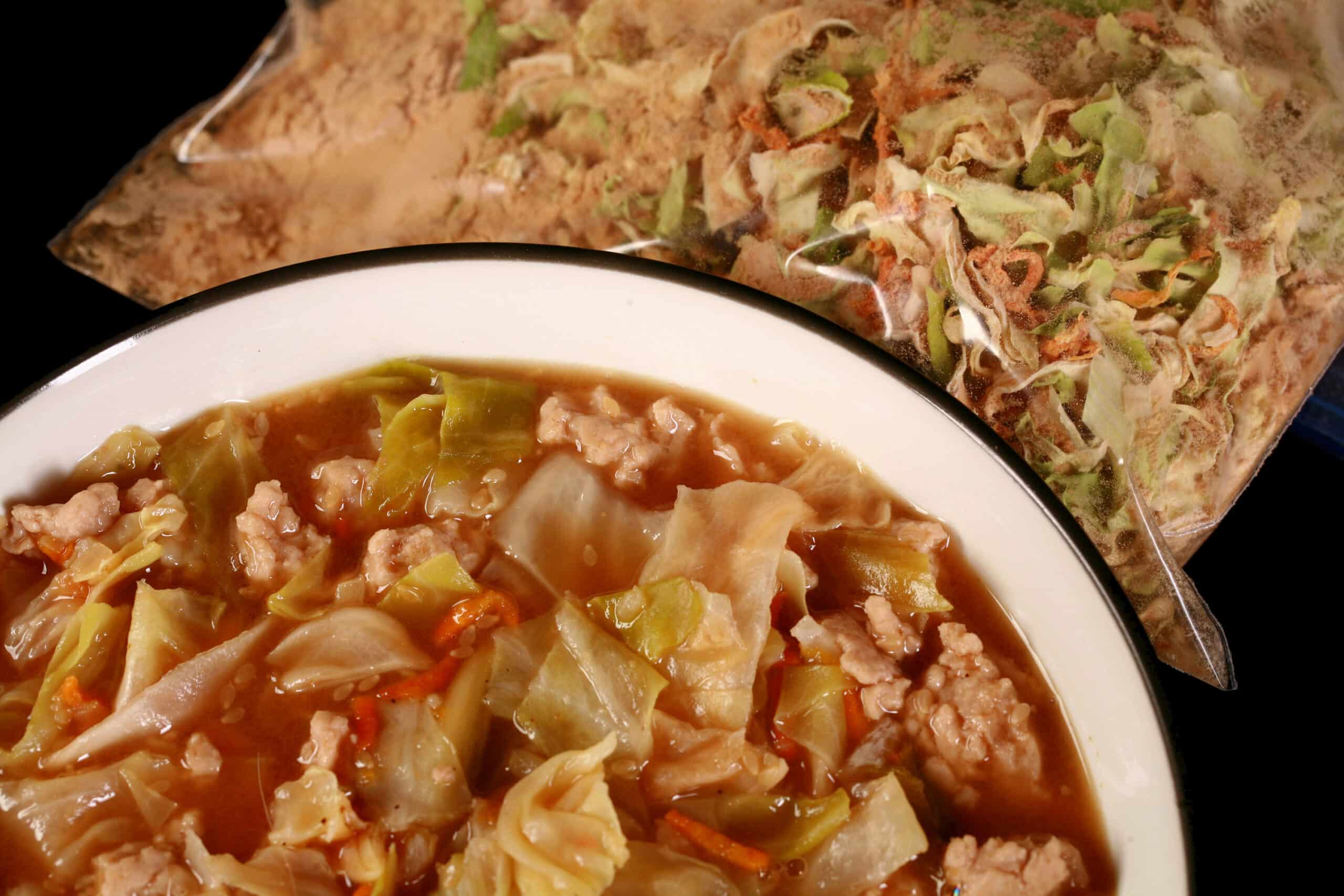 A bowl of keto egg roll soup in front of a bag of dry mix for the soup.