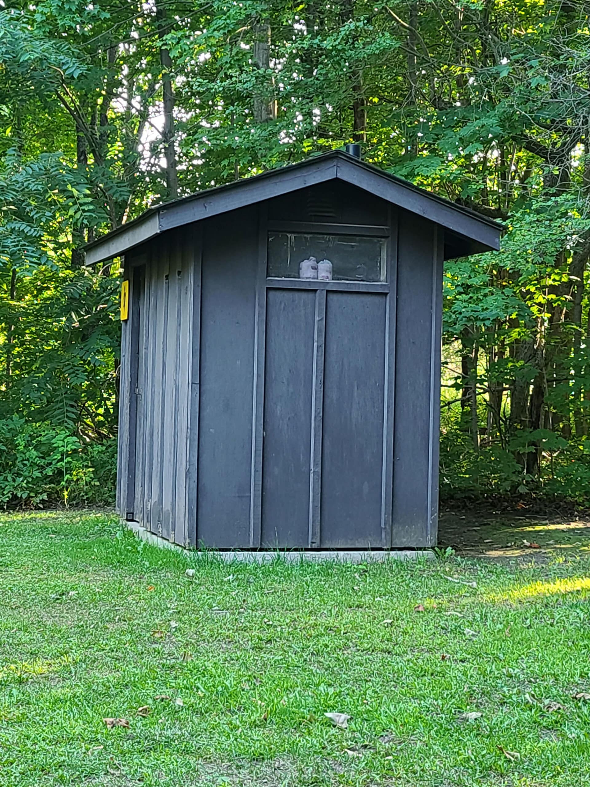 An outhouse in front of the woods.