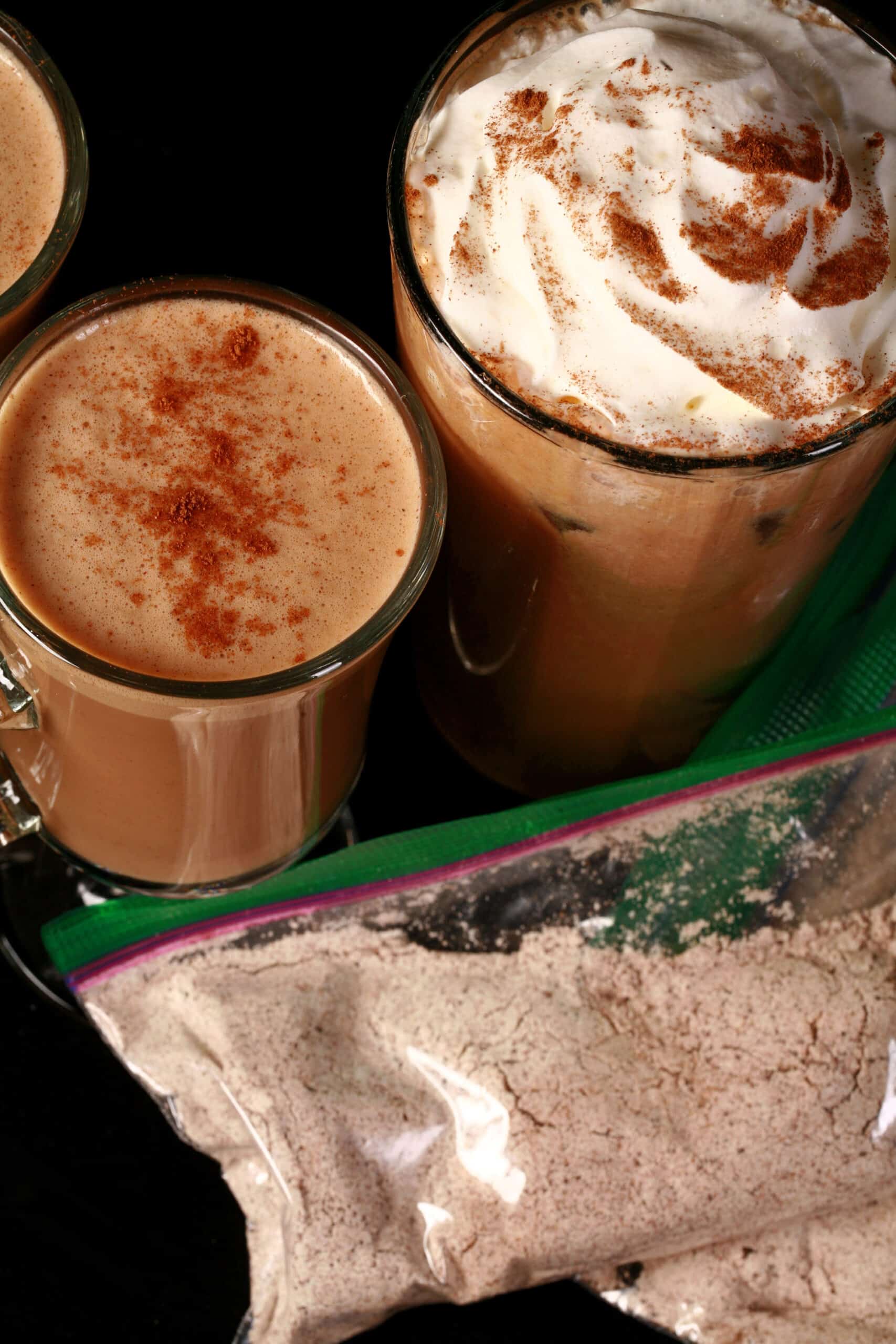 2 mugs of high protein gingerbread latte, a tall glass of protein powder iced gingerbread latte, and a few bags of the mix.