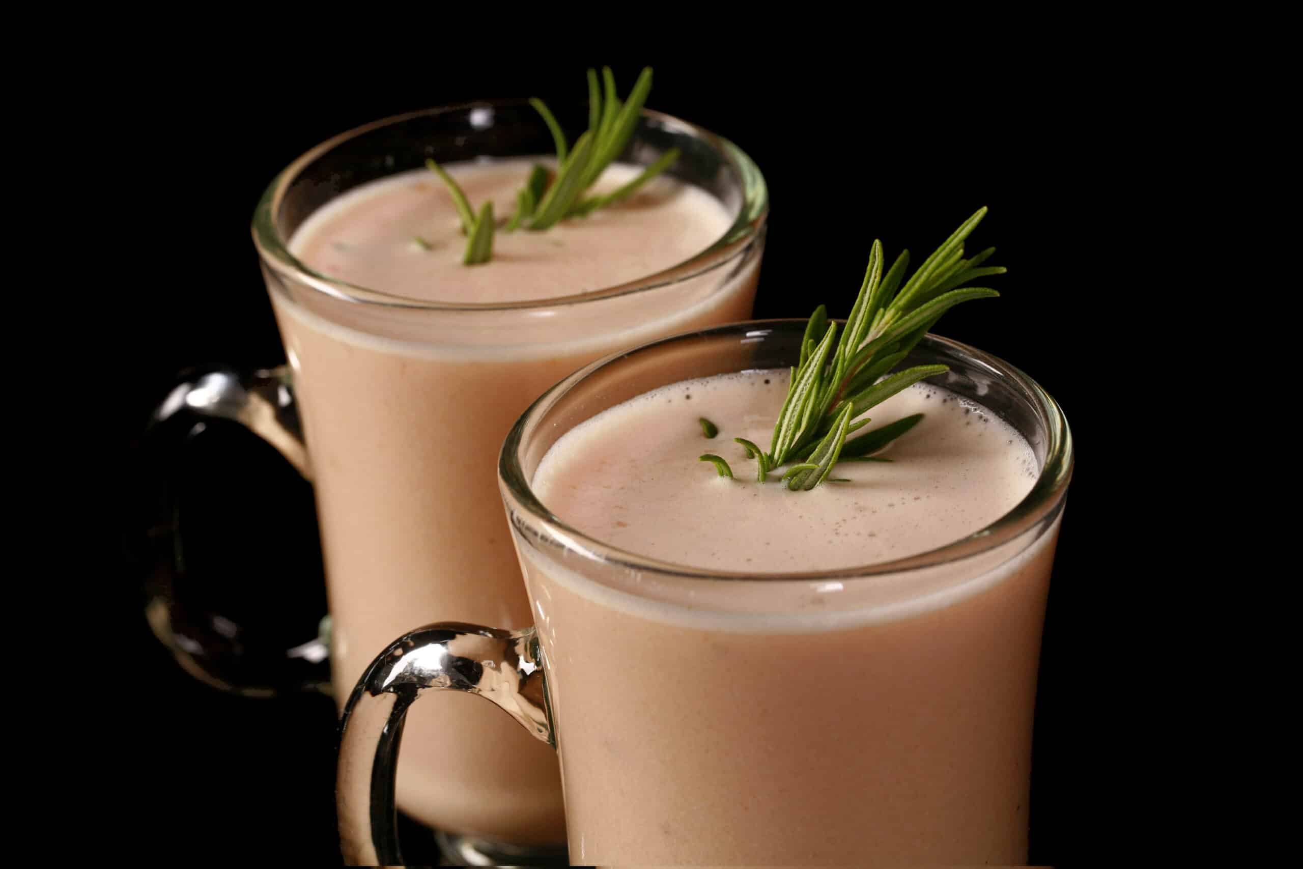 2 mugs of protein powder cream of chicken soup, garnished with rosemary sprigs.