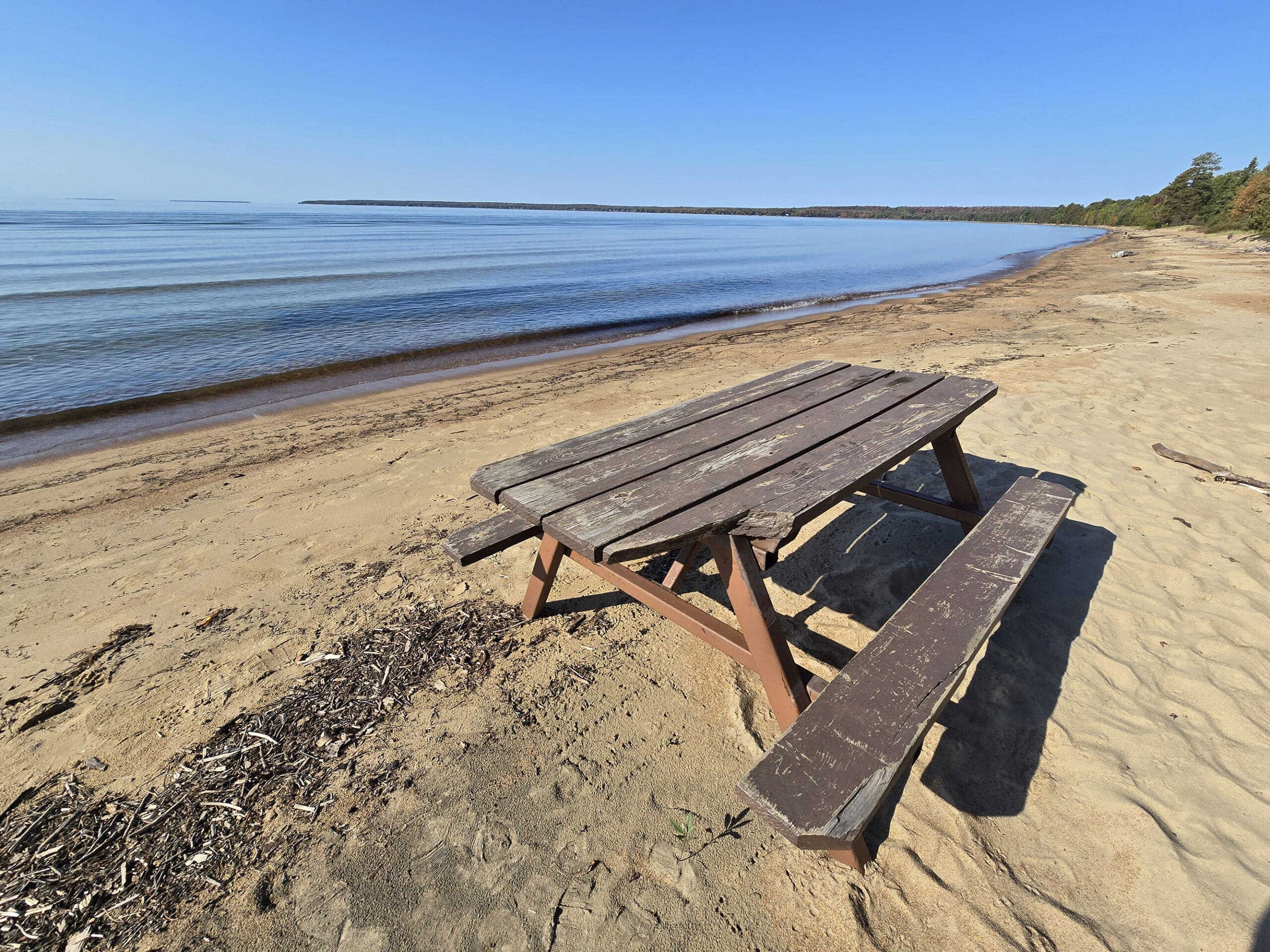 A picnic table on the beach at Batchawana Bay Provincial Park, with lake superior in the background.