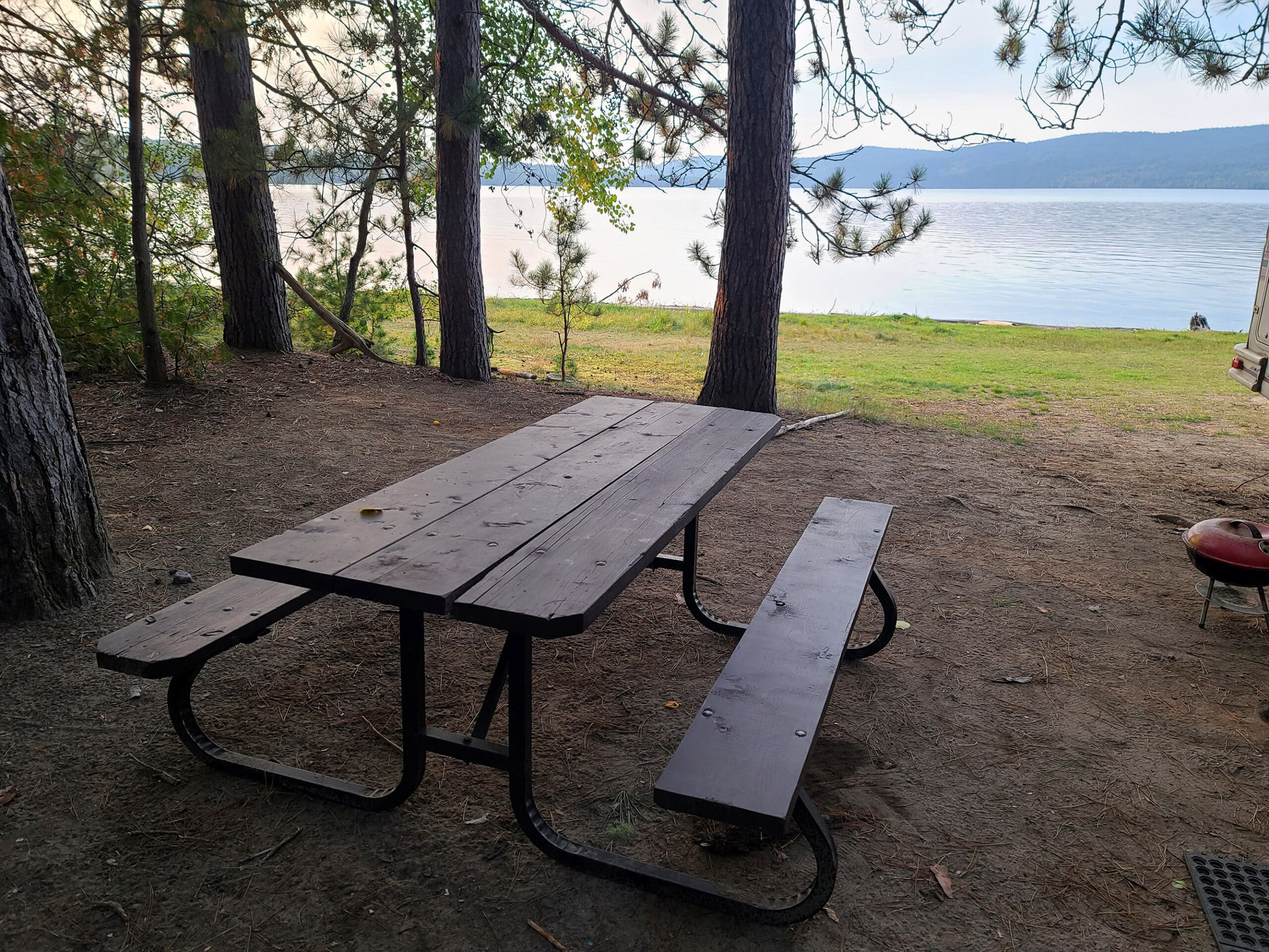 A large waterfront camp site with a picnic table in the foreground.