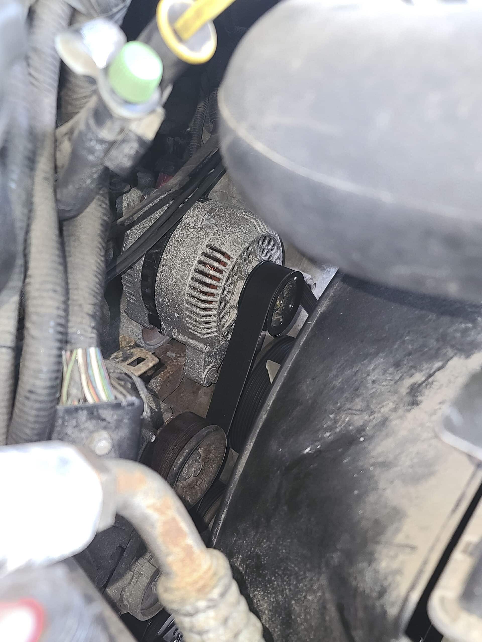 Under the hood of a motorhome, focused on the gray alternator with a black belt.