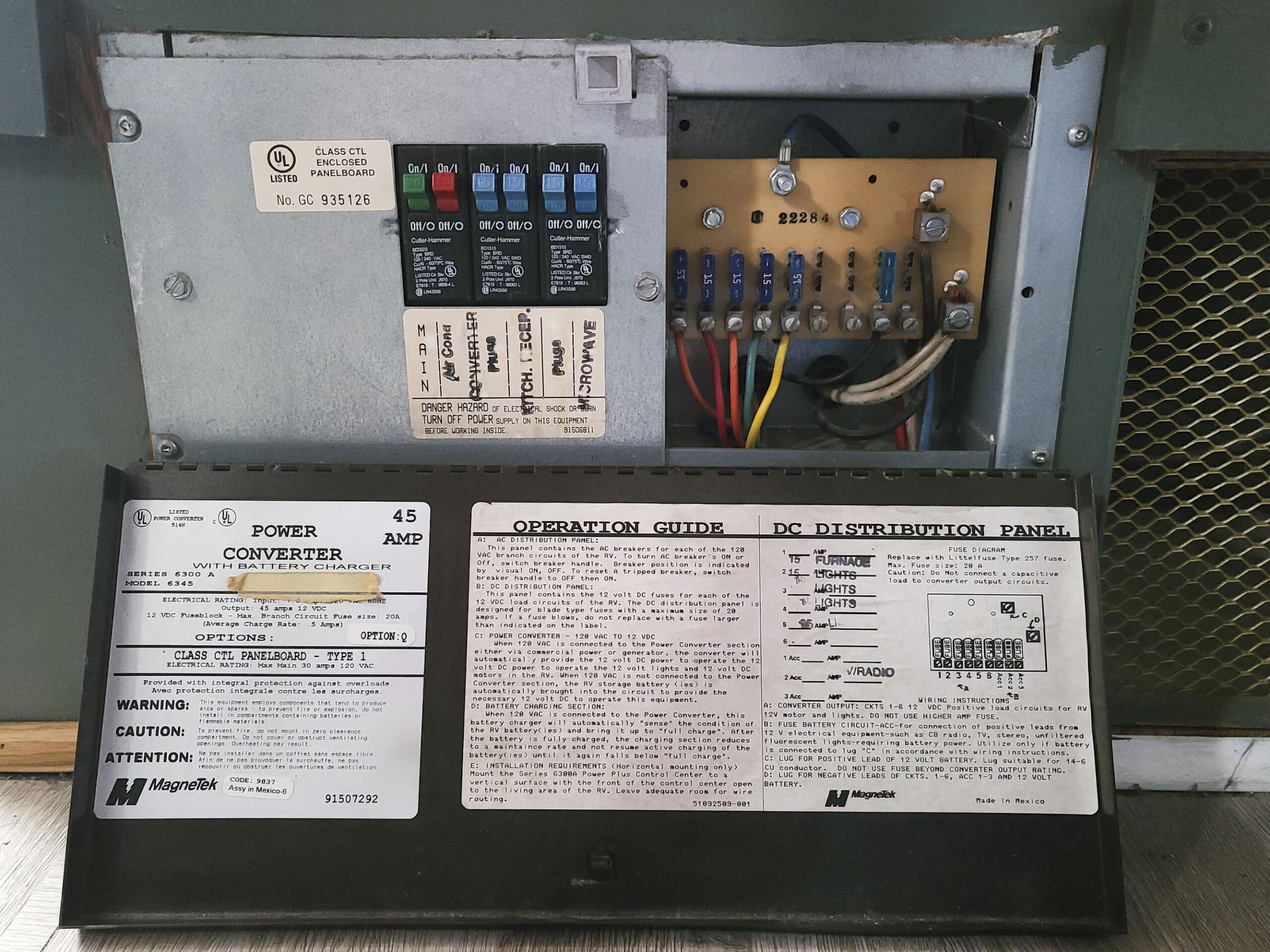 The front panel of an RV electrical box and power converter.  Circuit breakers are on the left, fuses are on the right, and the bottom contains instructions and specifications.