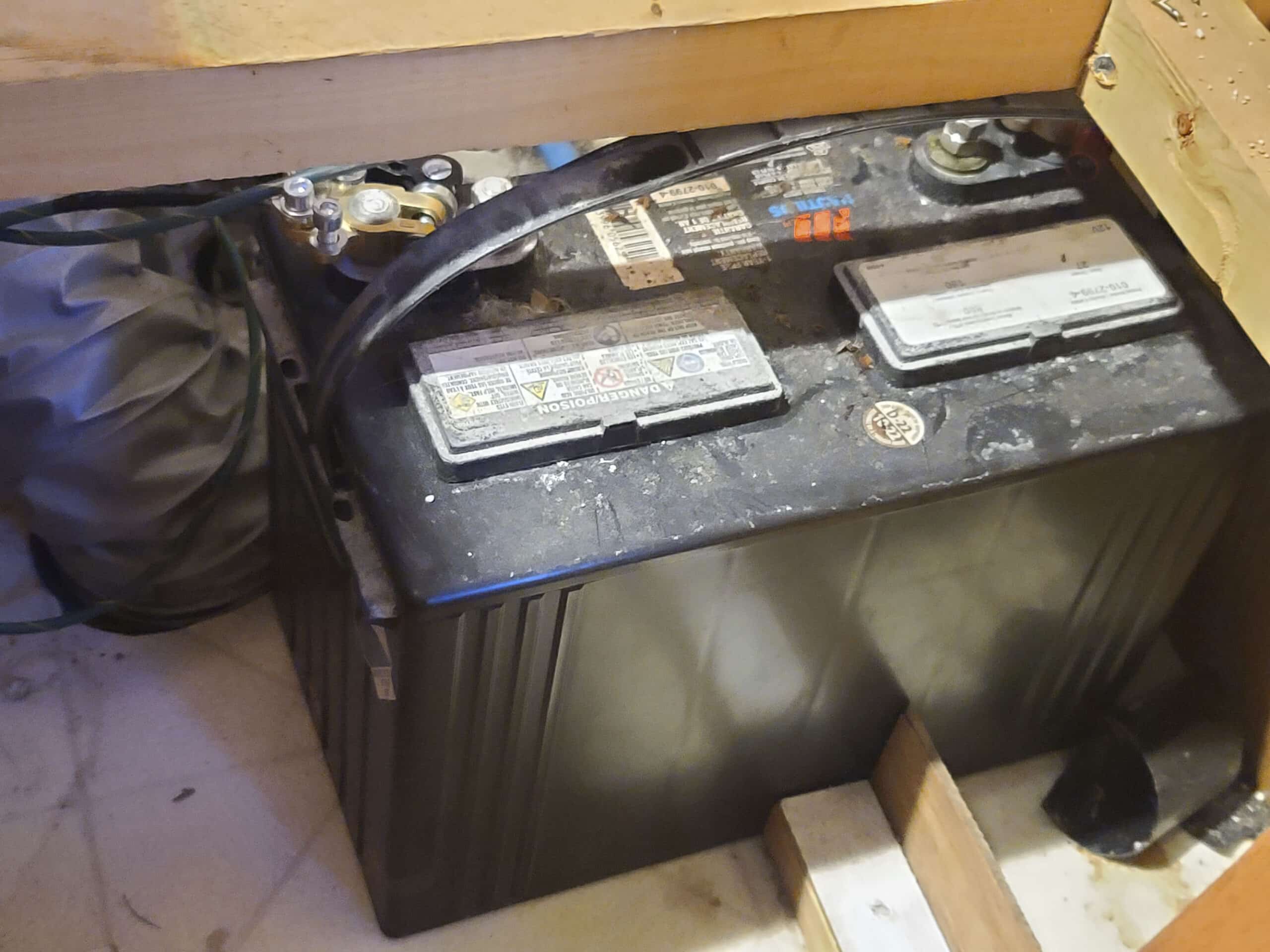 A top/side view of a deep cycle RV battery, seen under the kitchen seat.