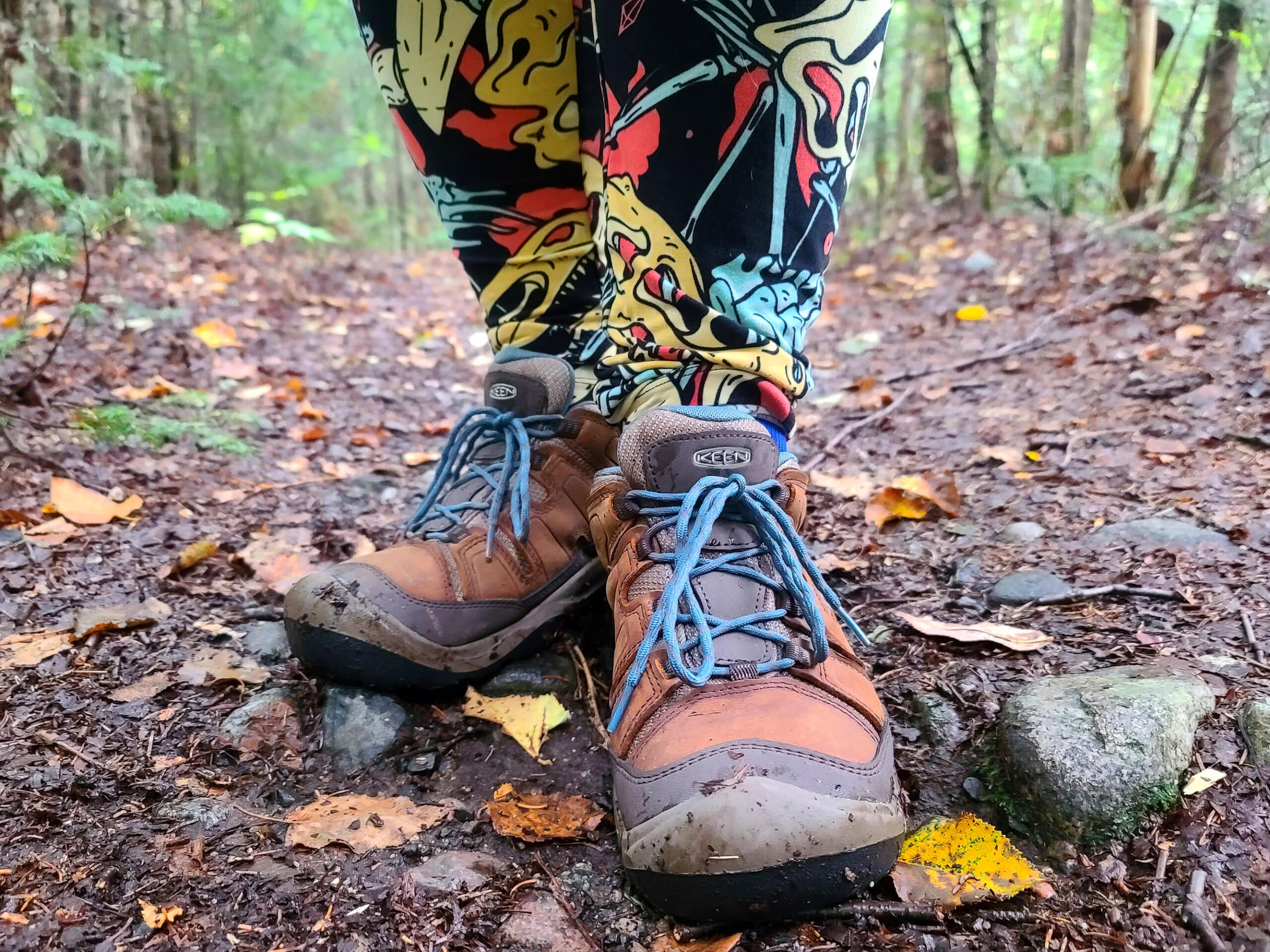 Feet and ankles of a woman wearing dinosaur themed tights and hiking boots.