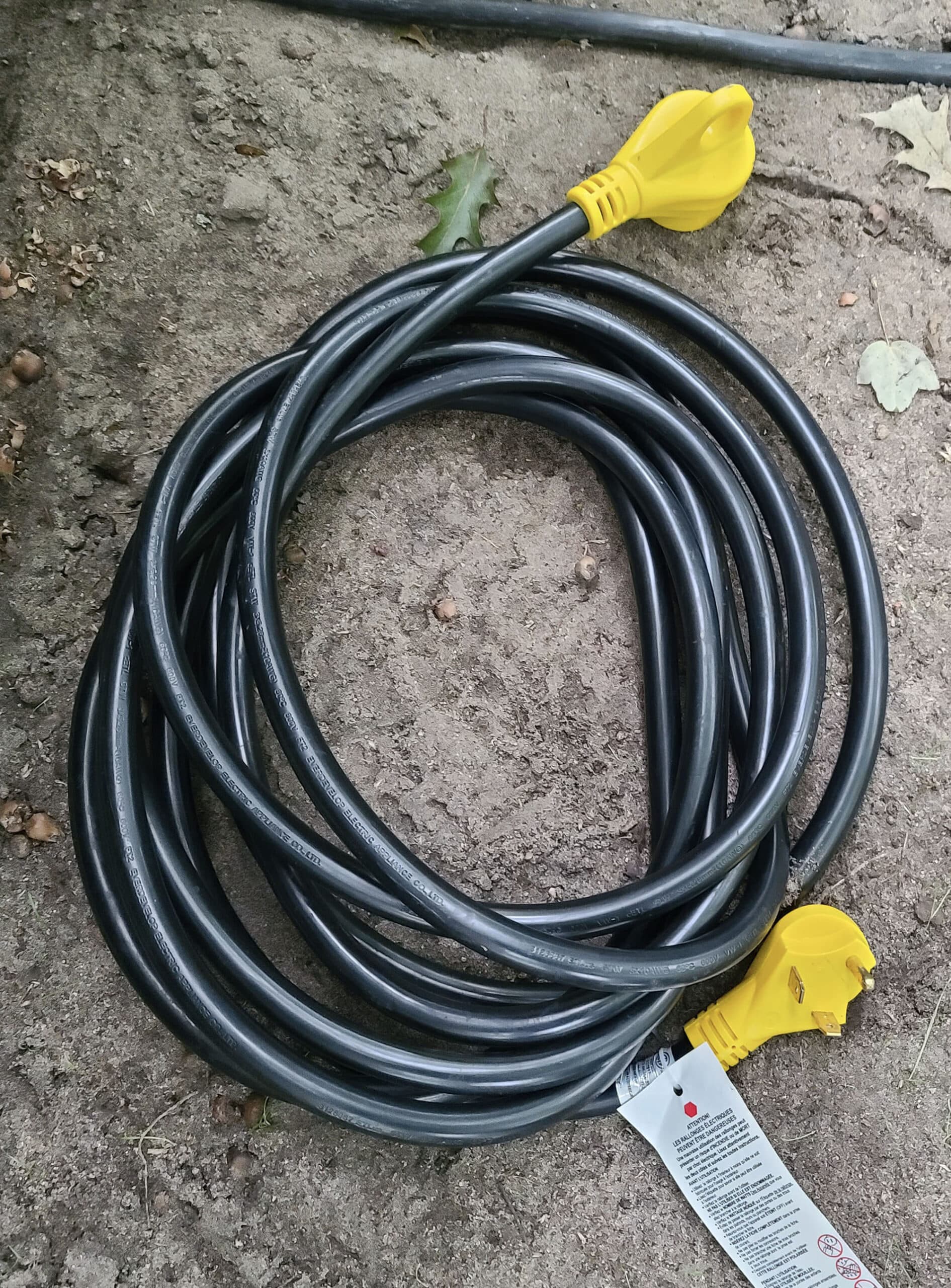 A black RV electrical cord is coiled on the ground.