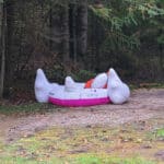 A deflated swan floating, wearing a personal flotation device, and an empty beer can.