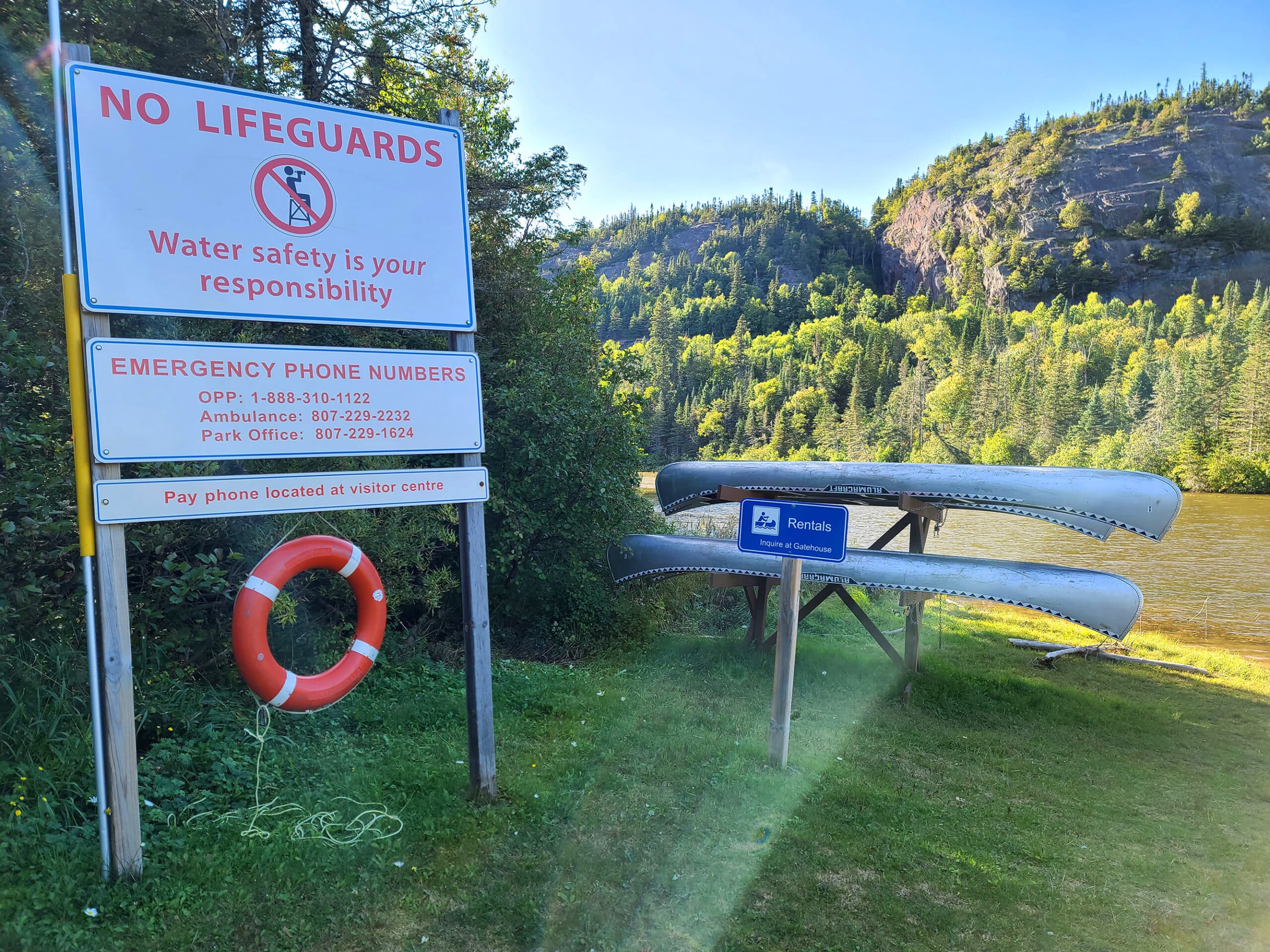 A canoe rack and a sign warning that there are no lifeguards on duty.