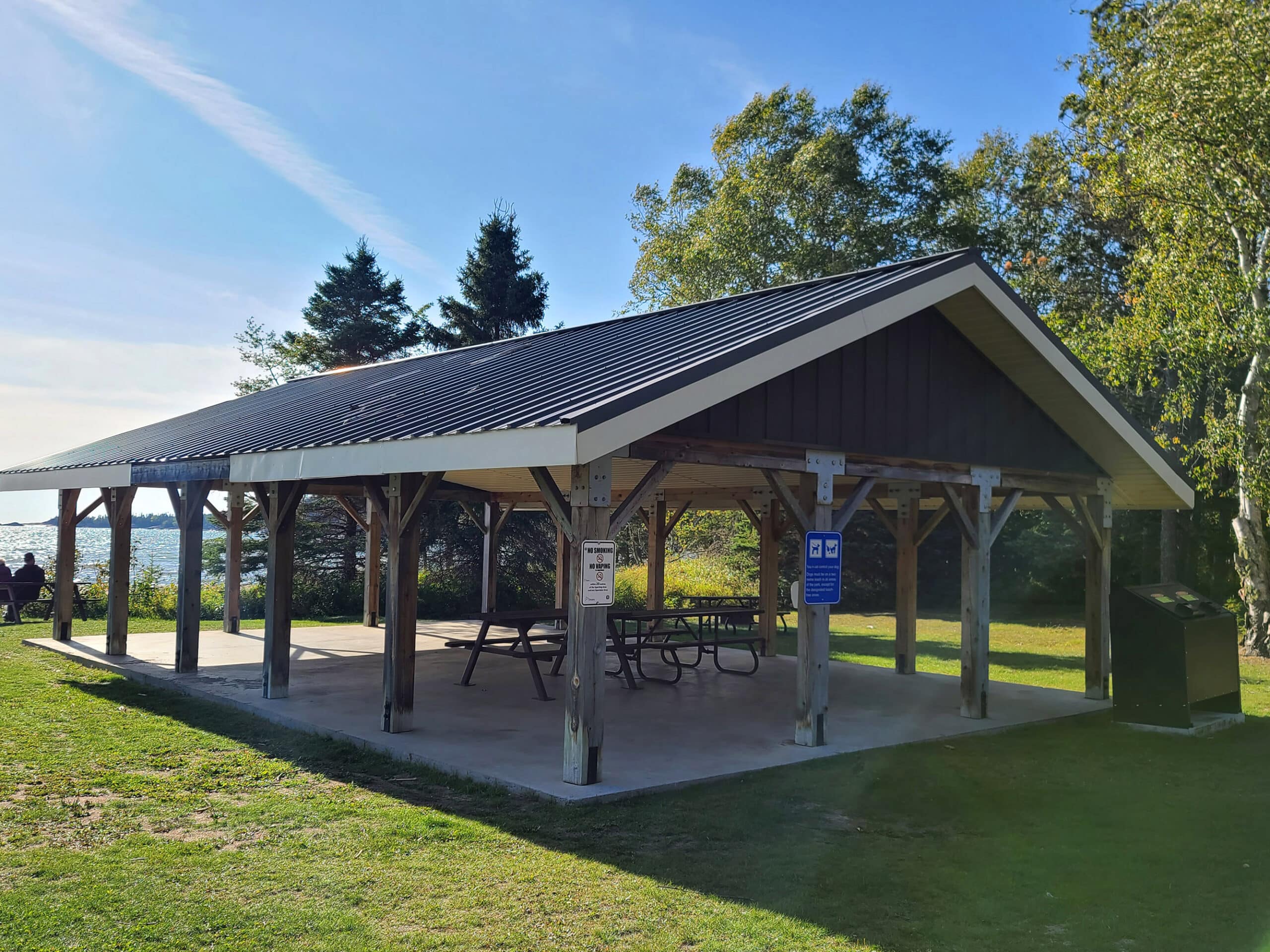 A covered picnic shelter with the lake behind it.
