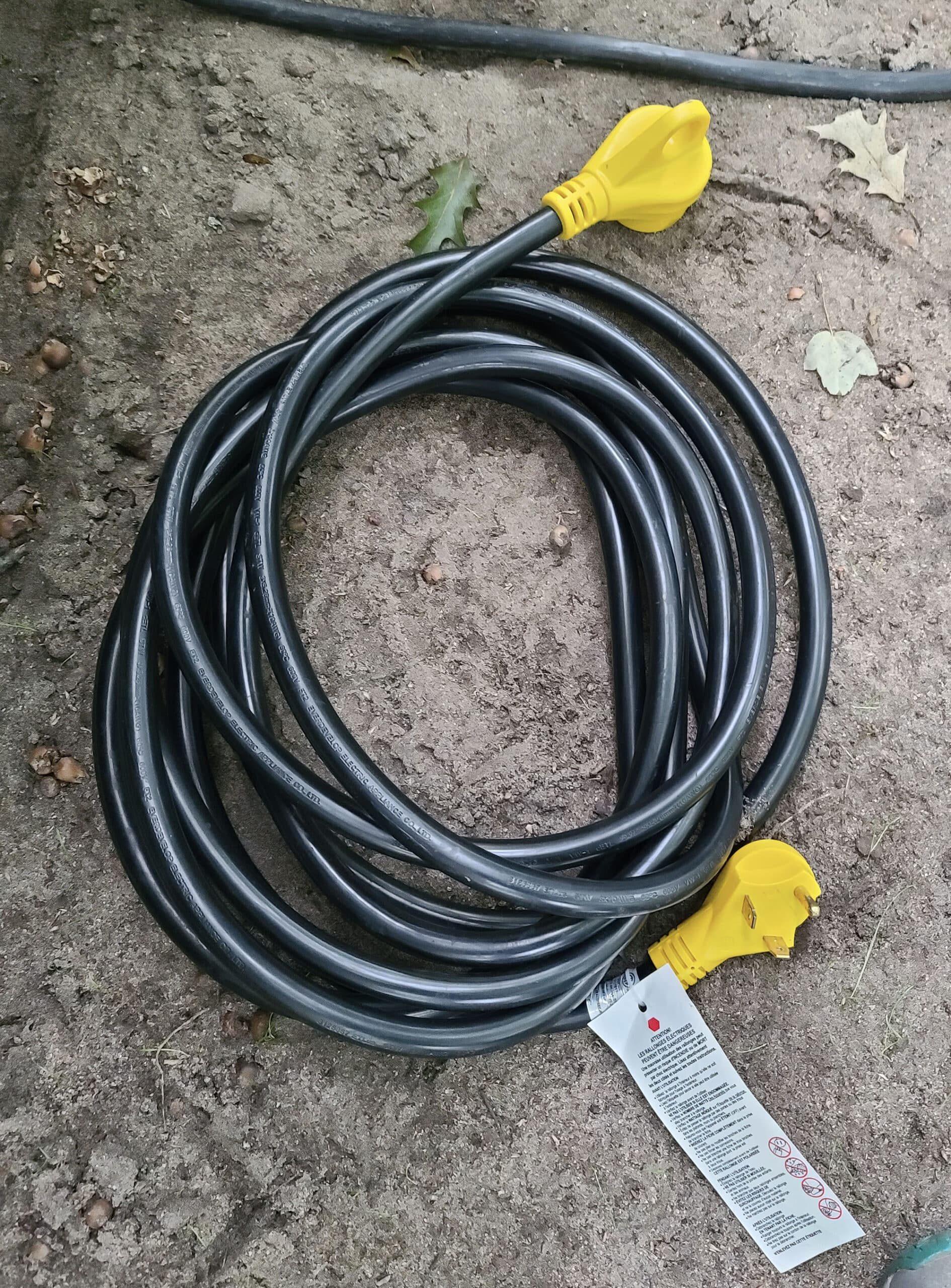 A black RV electrical cord coiled on the ground.