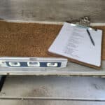 A clipboard with a paper checklist and pen, sitting on a step of an RV. There is a small level on the floor of the RV.
