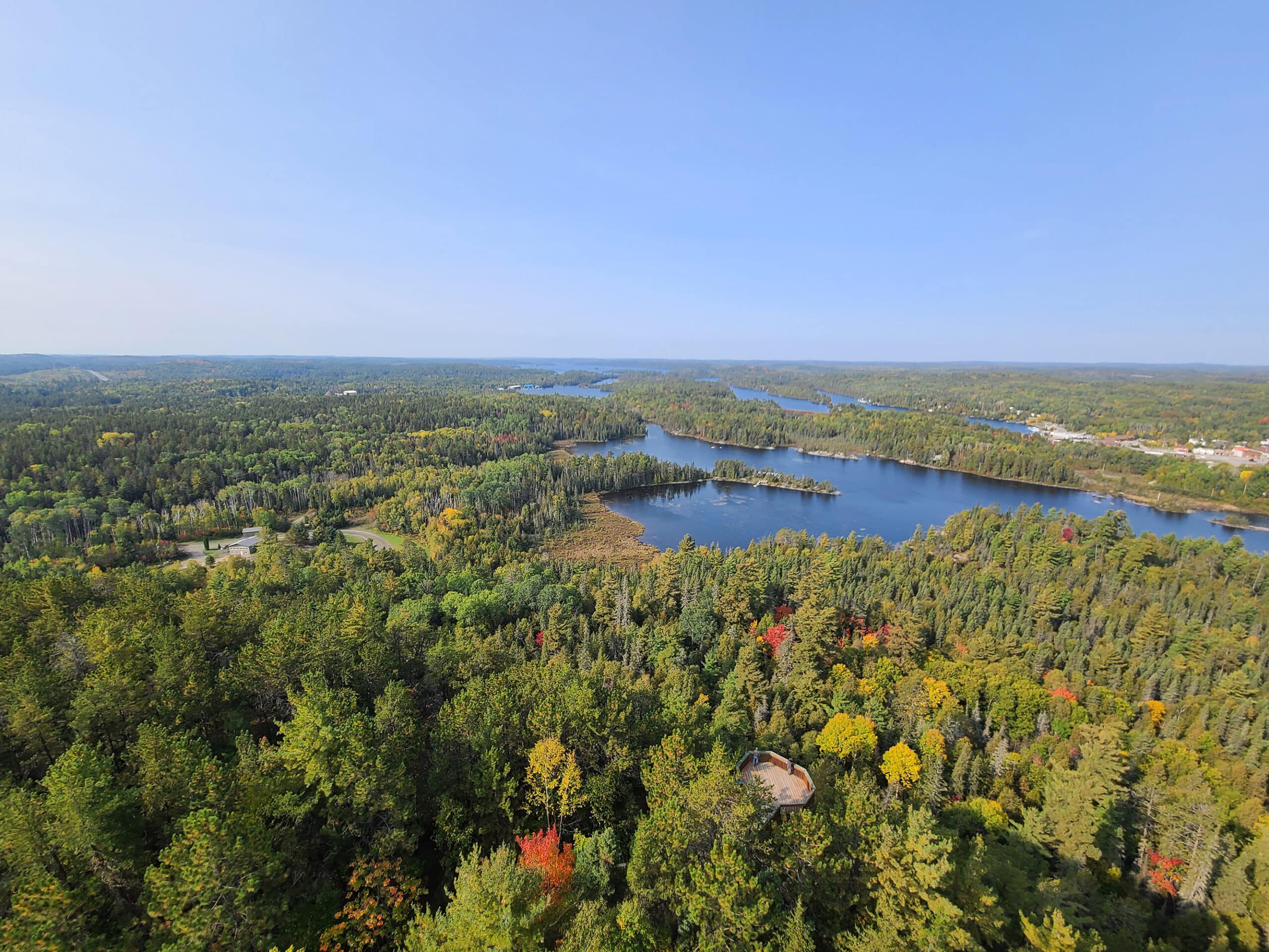 The view from the top of the temagami fire tower, looking out over trees and lakes in the surrounding area.