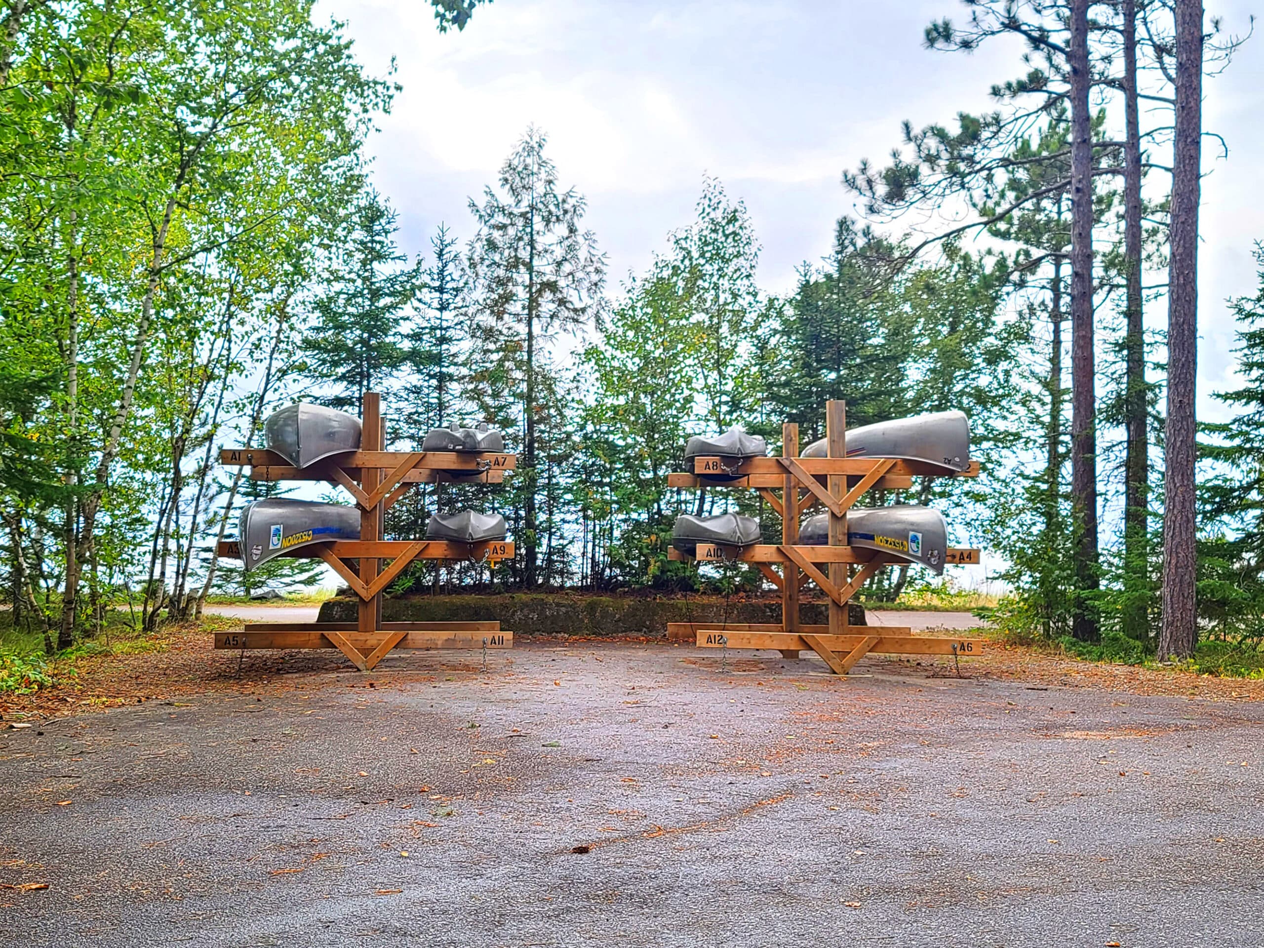 A rack of canoes with trees and lake superior in the background.