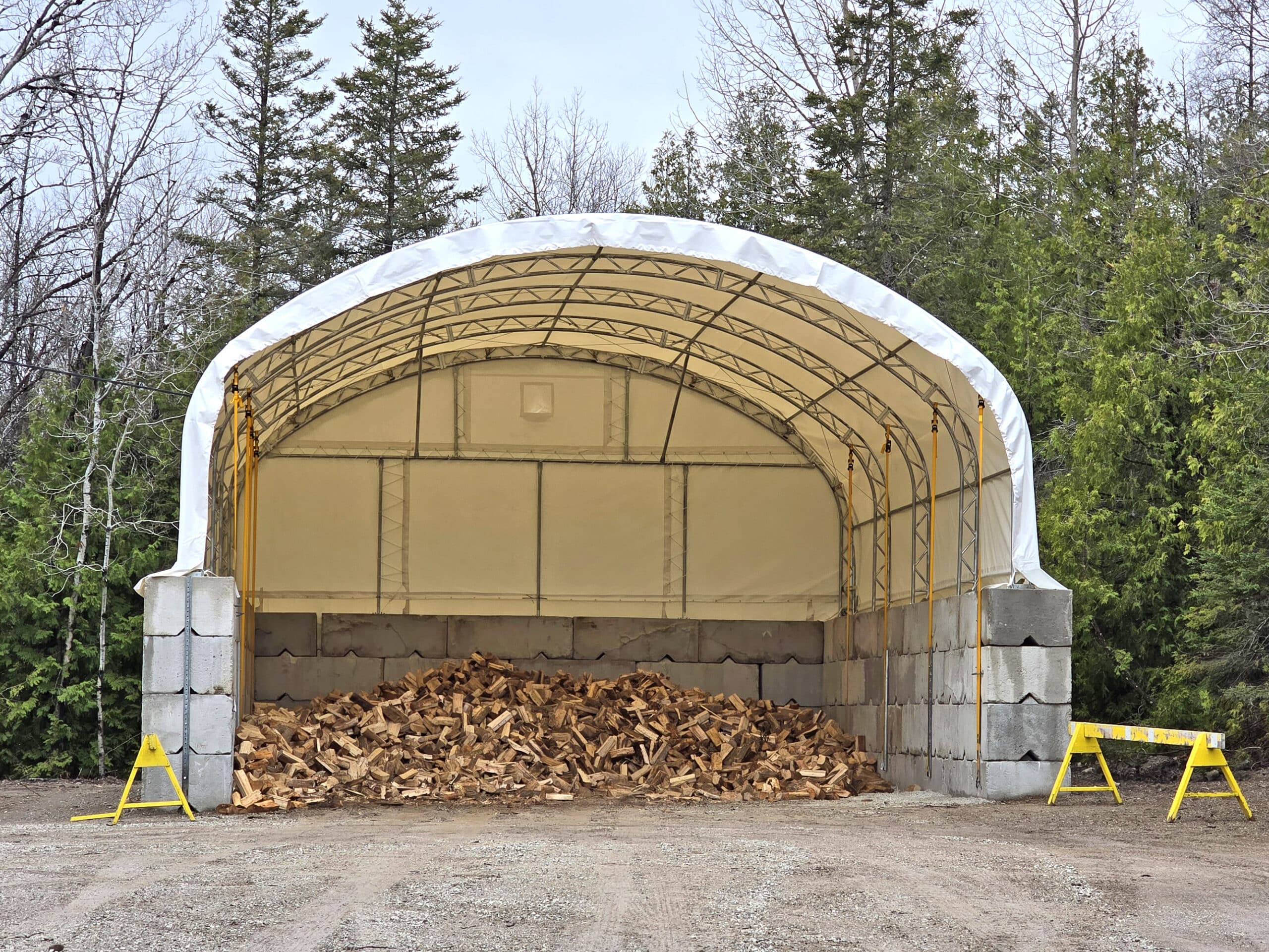 A big pile of wood under a large canopy.