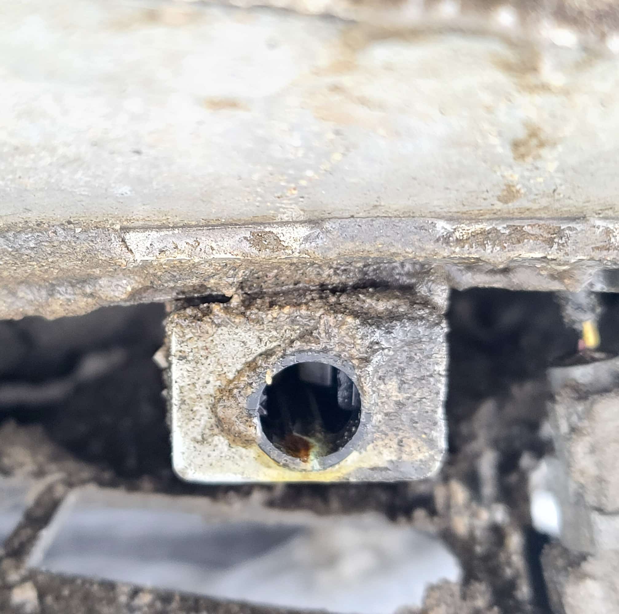 A small metal device mounted underneath a bumper.  It has a hole in the center.