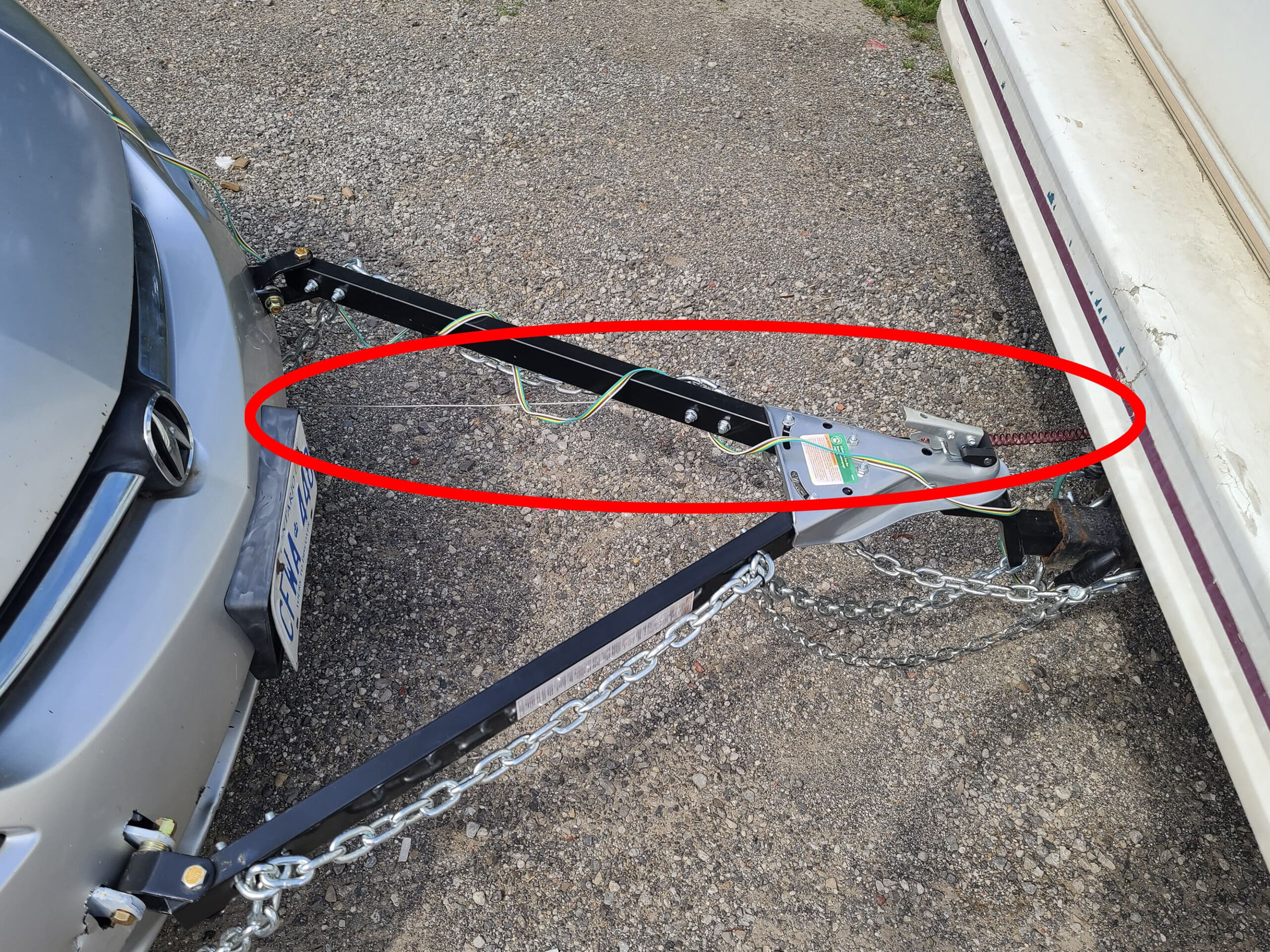 A tow bar setup between a car and a motorhome.  A red circle indicates the breakaway switch cable.