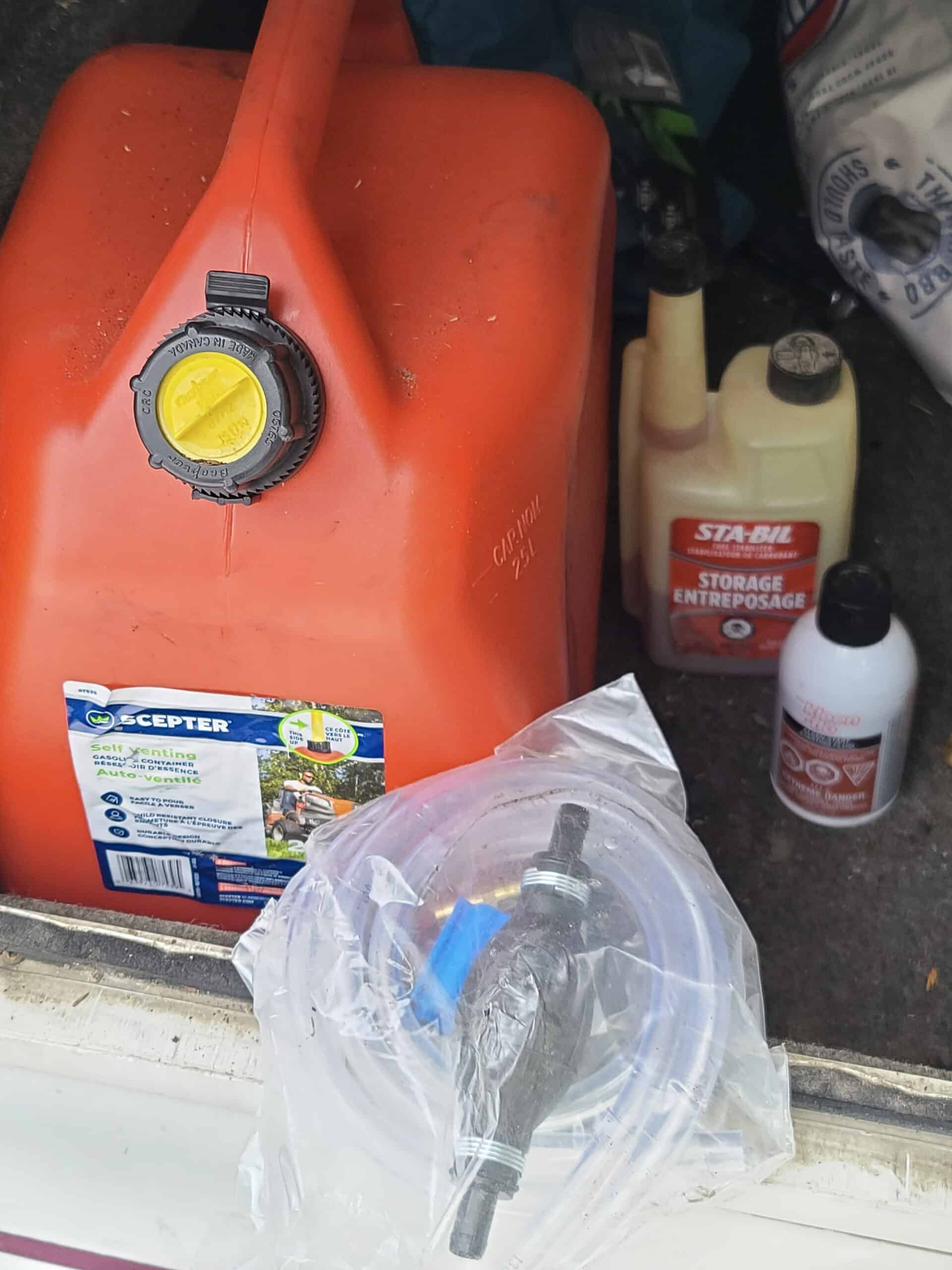 A red gas container, a bottle of Sta-bil, engine starter spray, and a gas siphon kit.