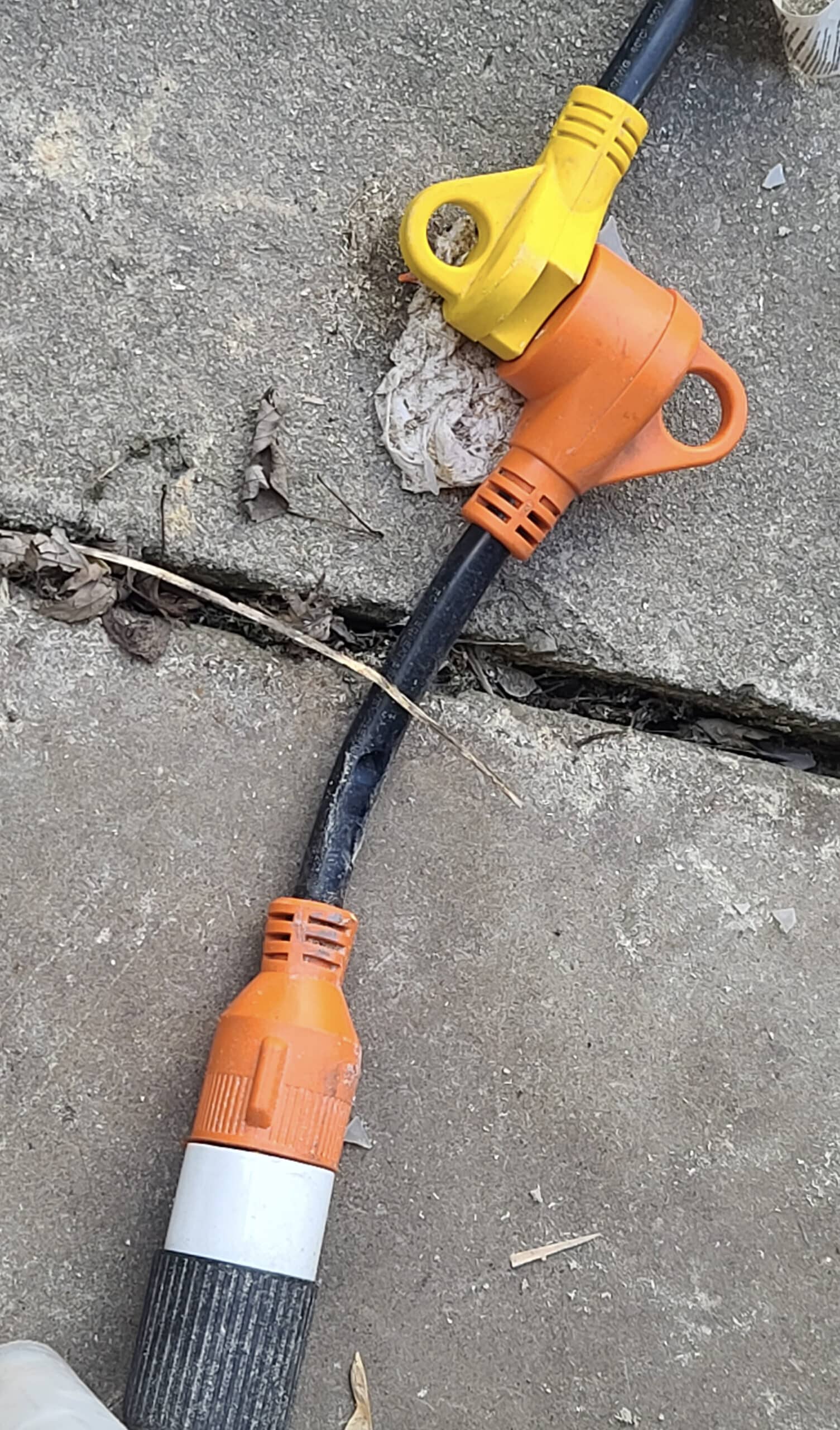 An orange power adapter between a yellow plug and a black plug of different types.