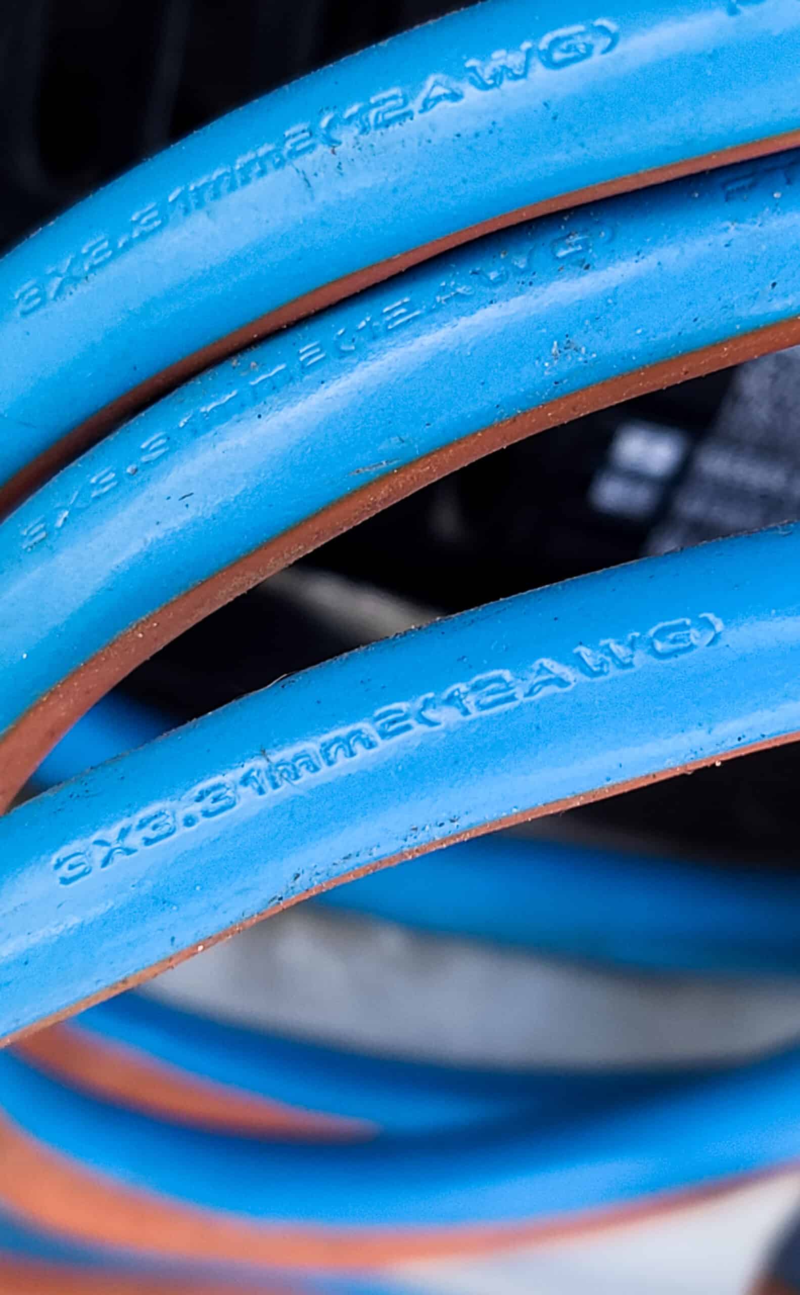 A blue power cable with stamped writing on the cable.  The writing states it is 12AWG wire.