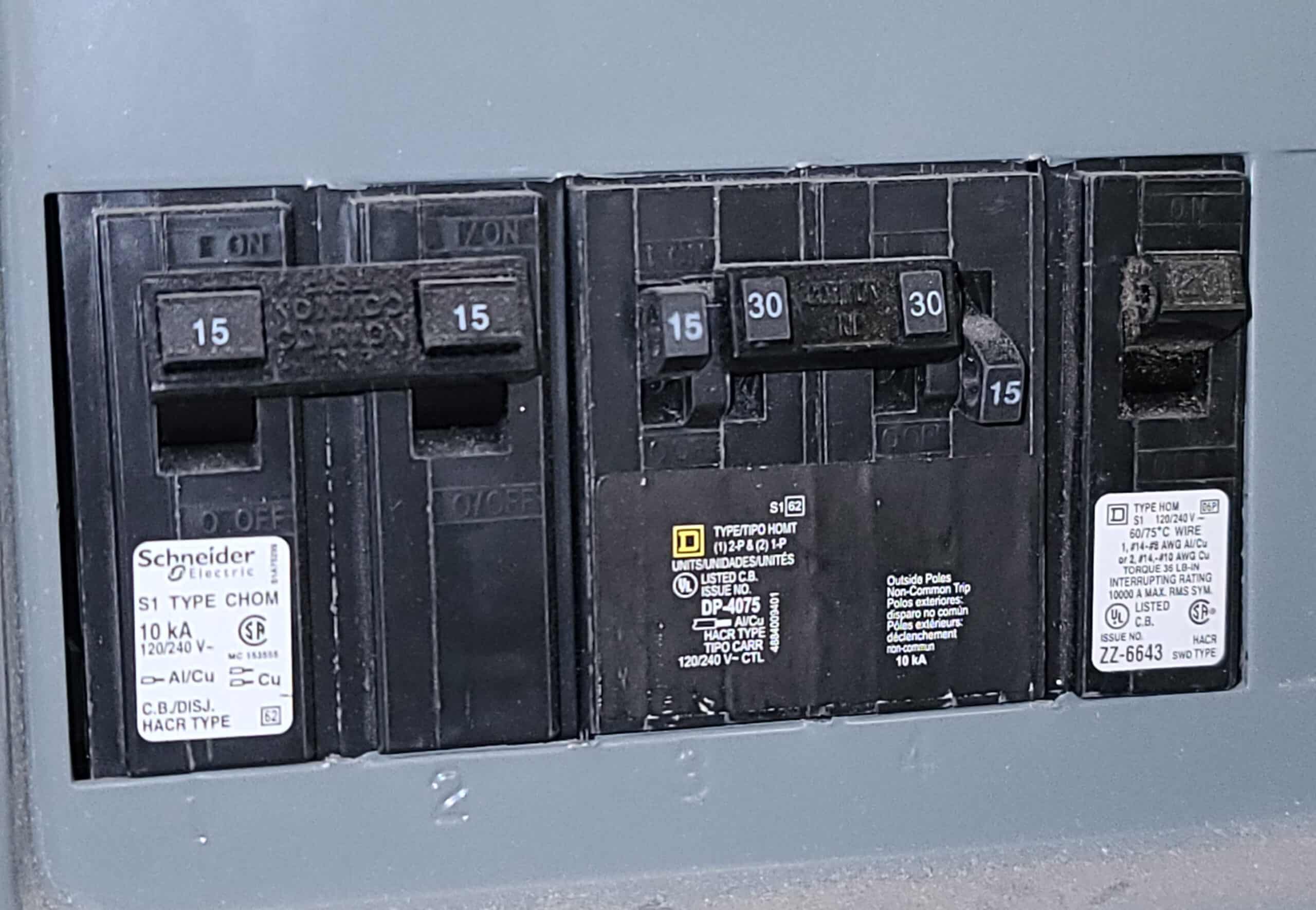 A circuit breaker box with various types of black circuit breakers.