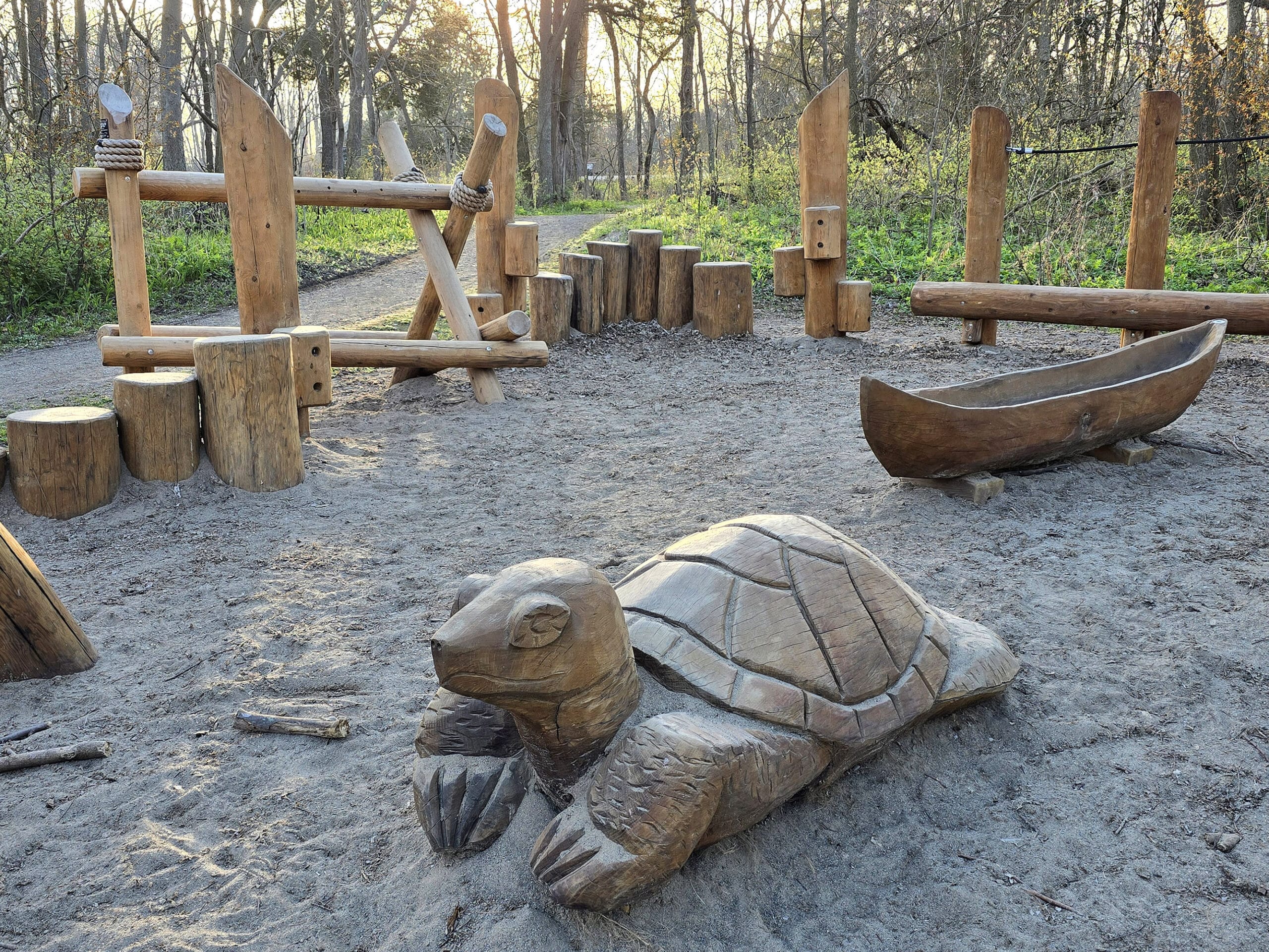 Various wooden sculptures in a sandy area.