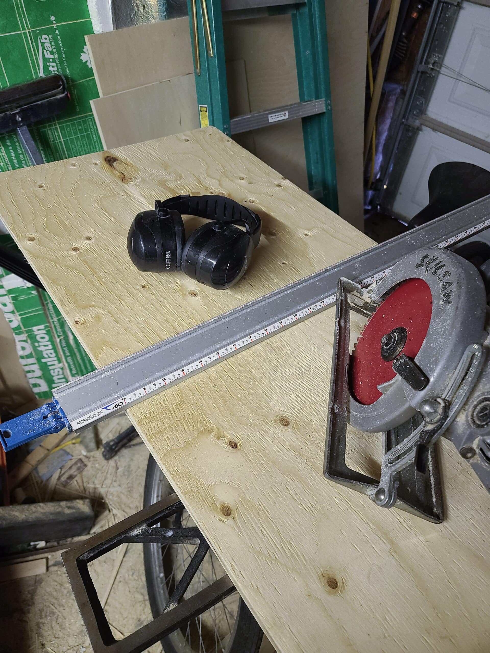 A large piece of plywood, a cutting straight edge, a pair of hearing protection muffs, and a worm drive circular saw.