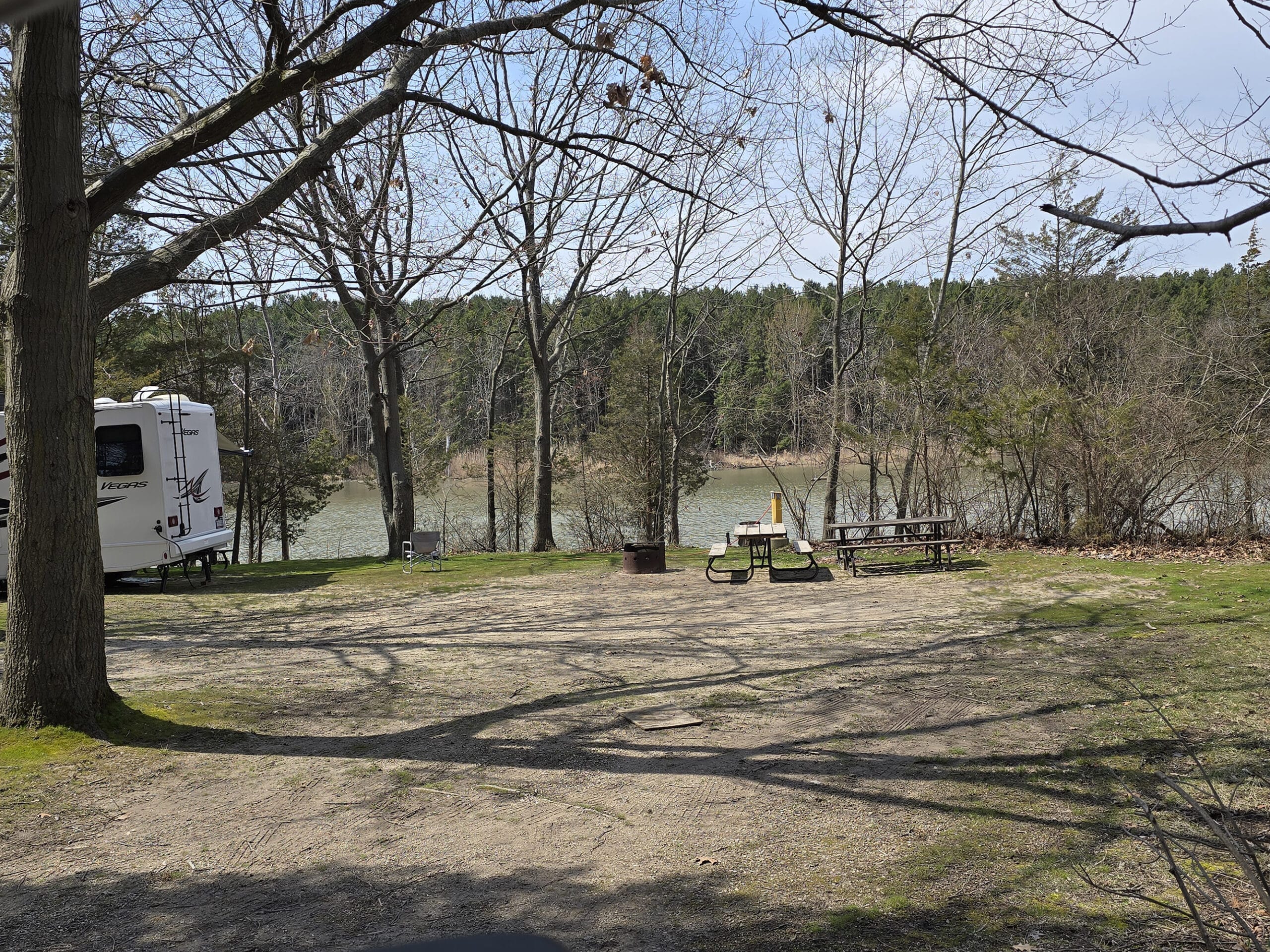 A campsite overlooking a creek, with the back end of another RV in the shot.