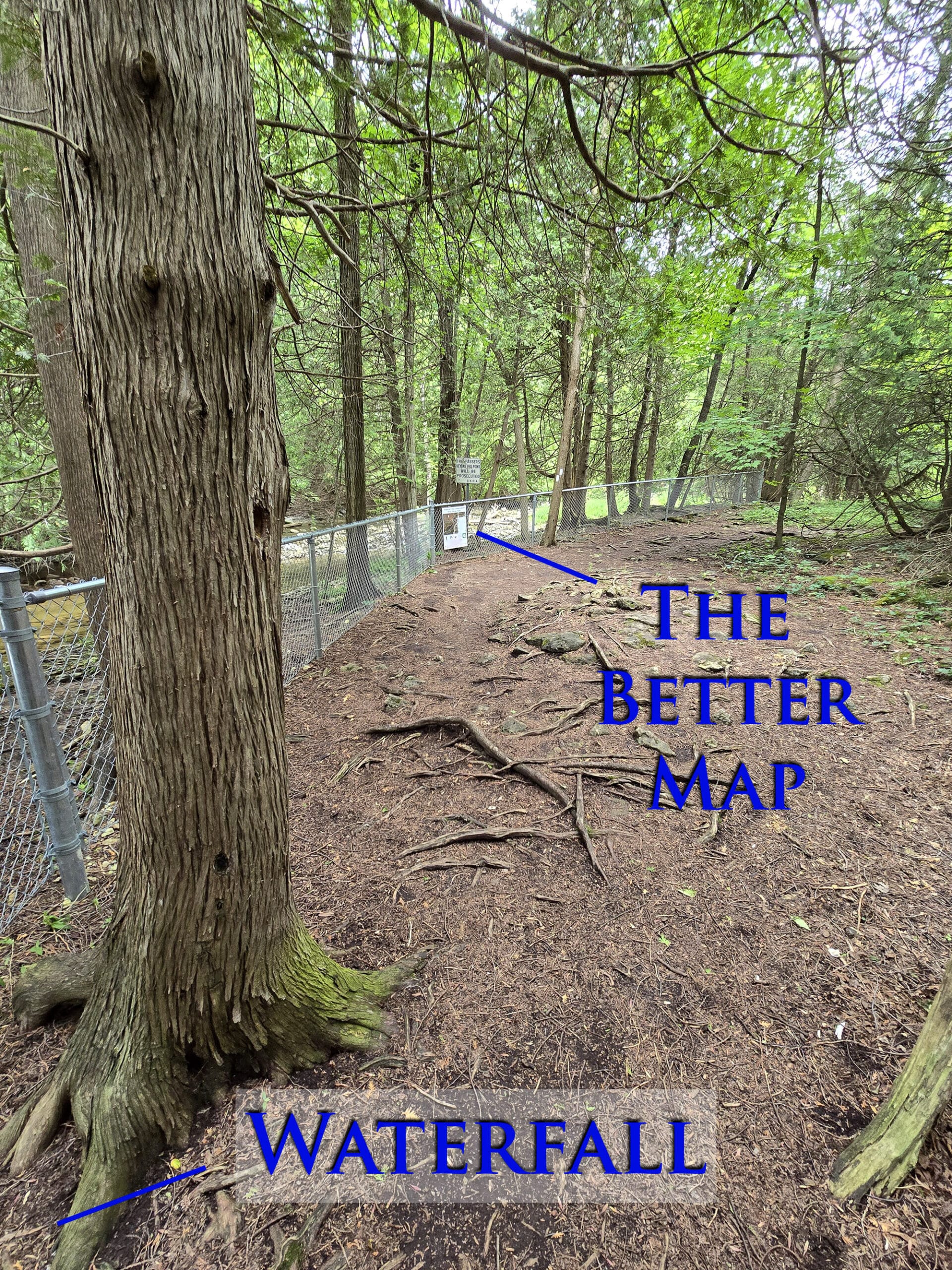 A zoomed out view of a trail, with a sign on a fence in the distance.  Overlaid text indicates the sign to be the better map.