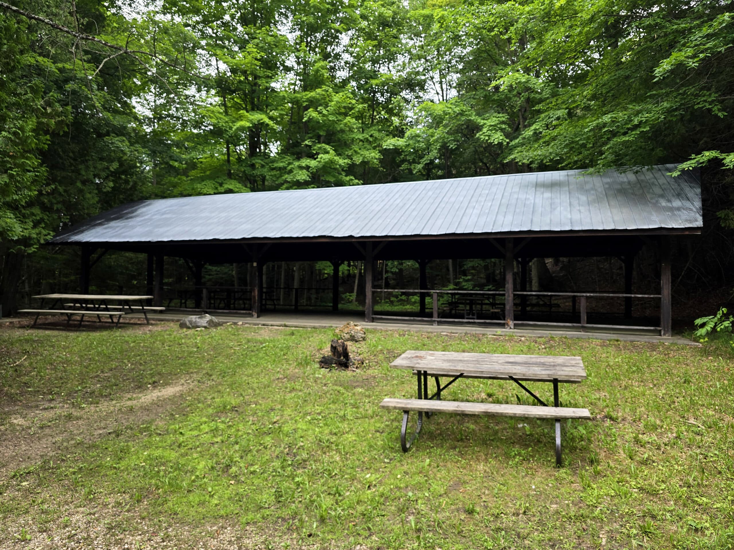 A covered picnic shelter with another picnic table in the foreground.